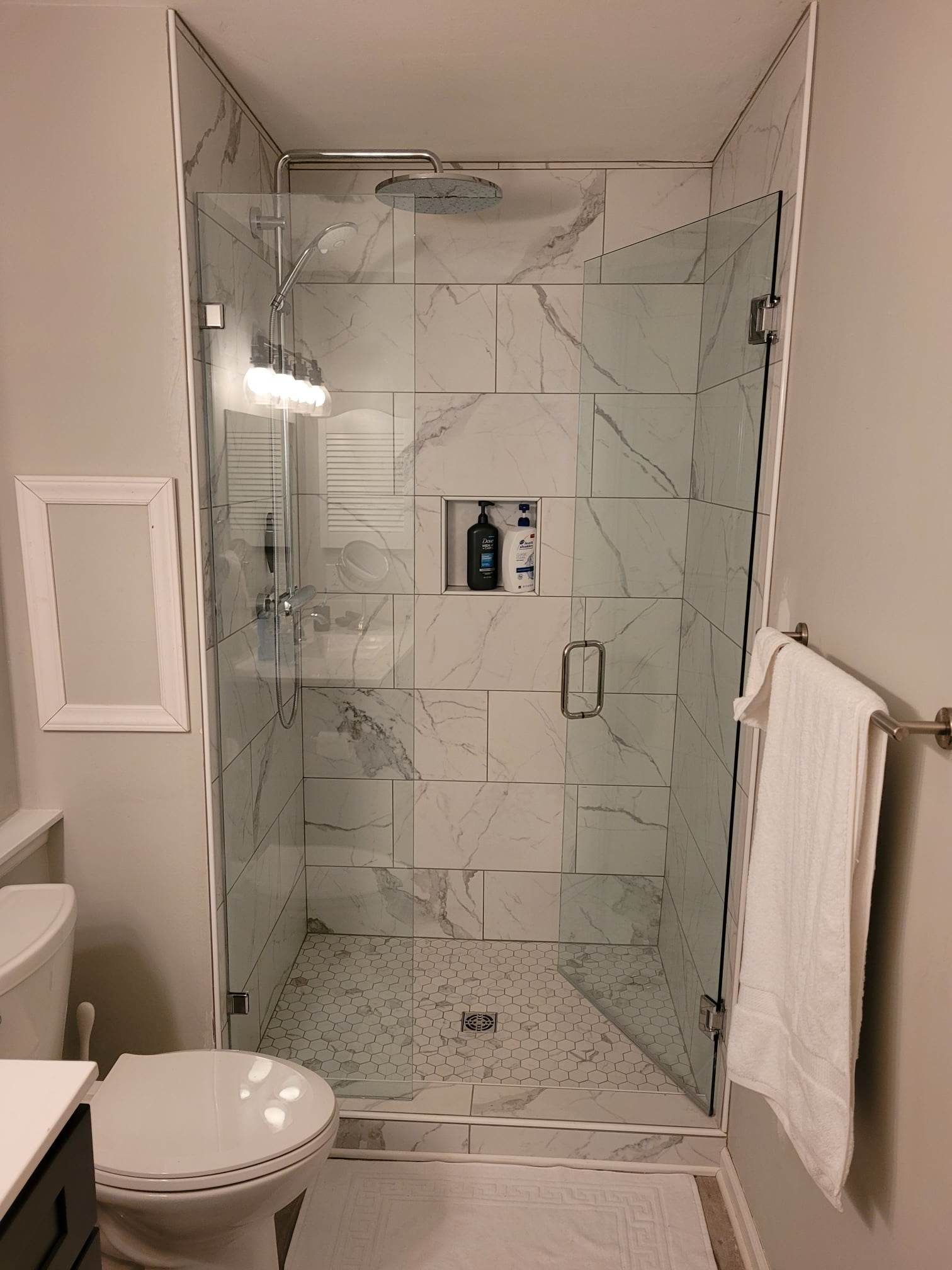 A bathroom with a toilet and a walk in shower with a glass door.