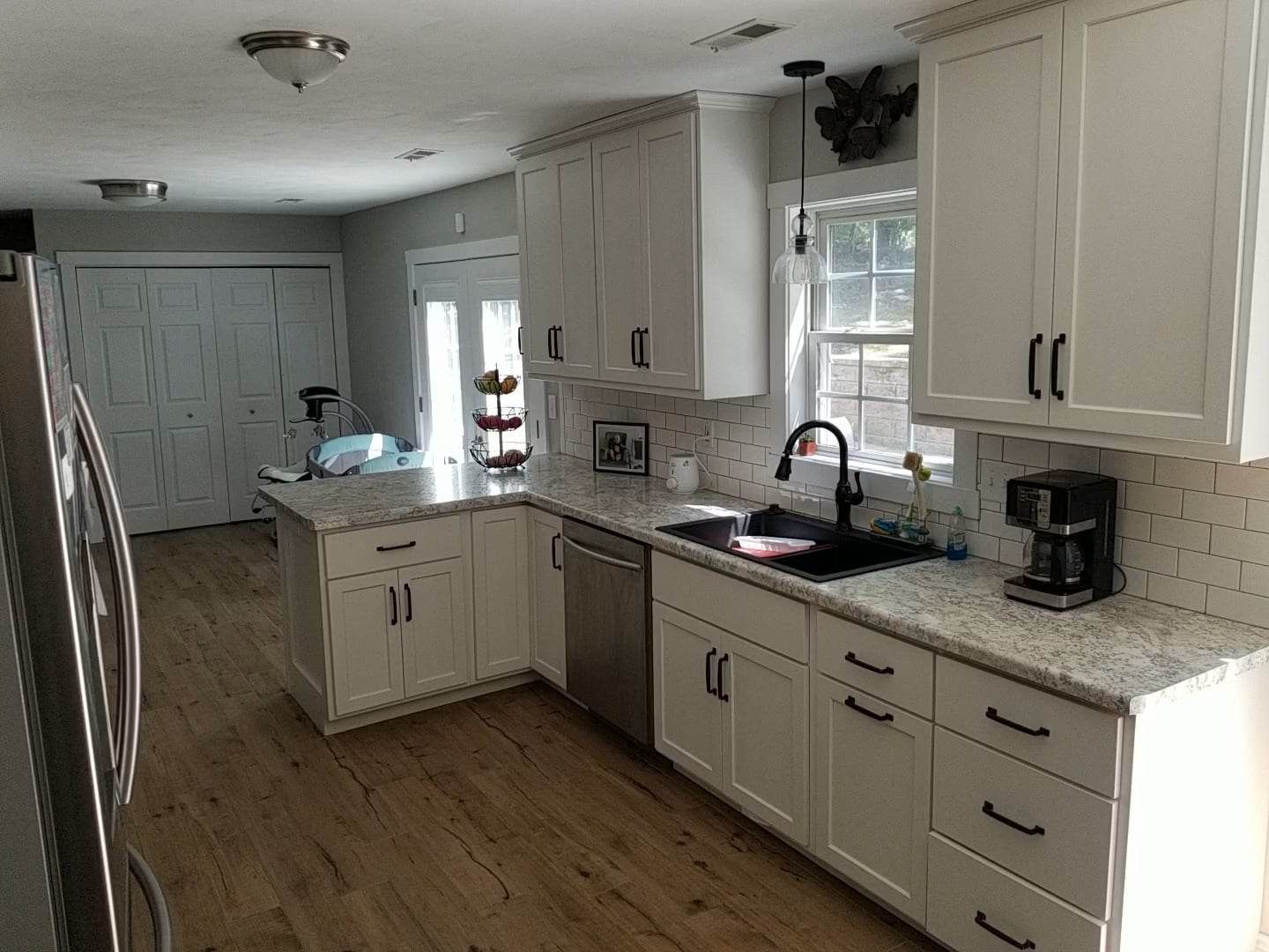 A kitchen with white cabinets , granite counter tops , and stainless steel appliances.