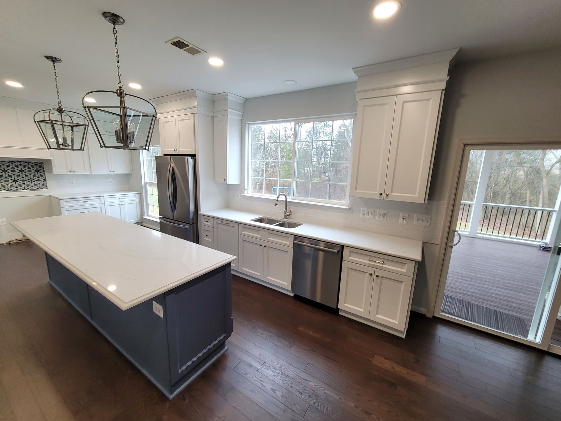 A kitchen with white cabinets , stainless steel appliances , and a large island.