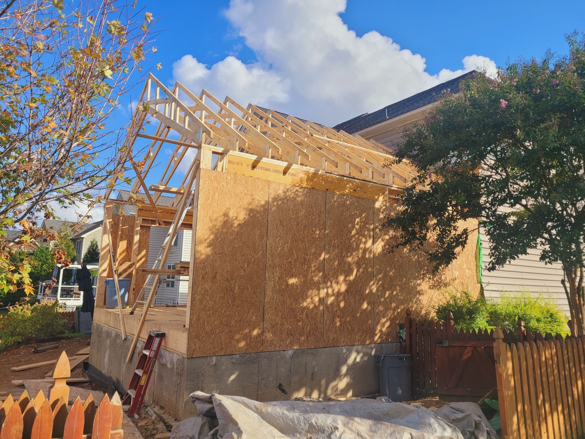 A house is being built with a ladder in the backyard.
