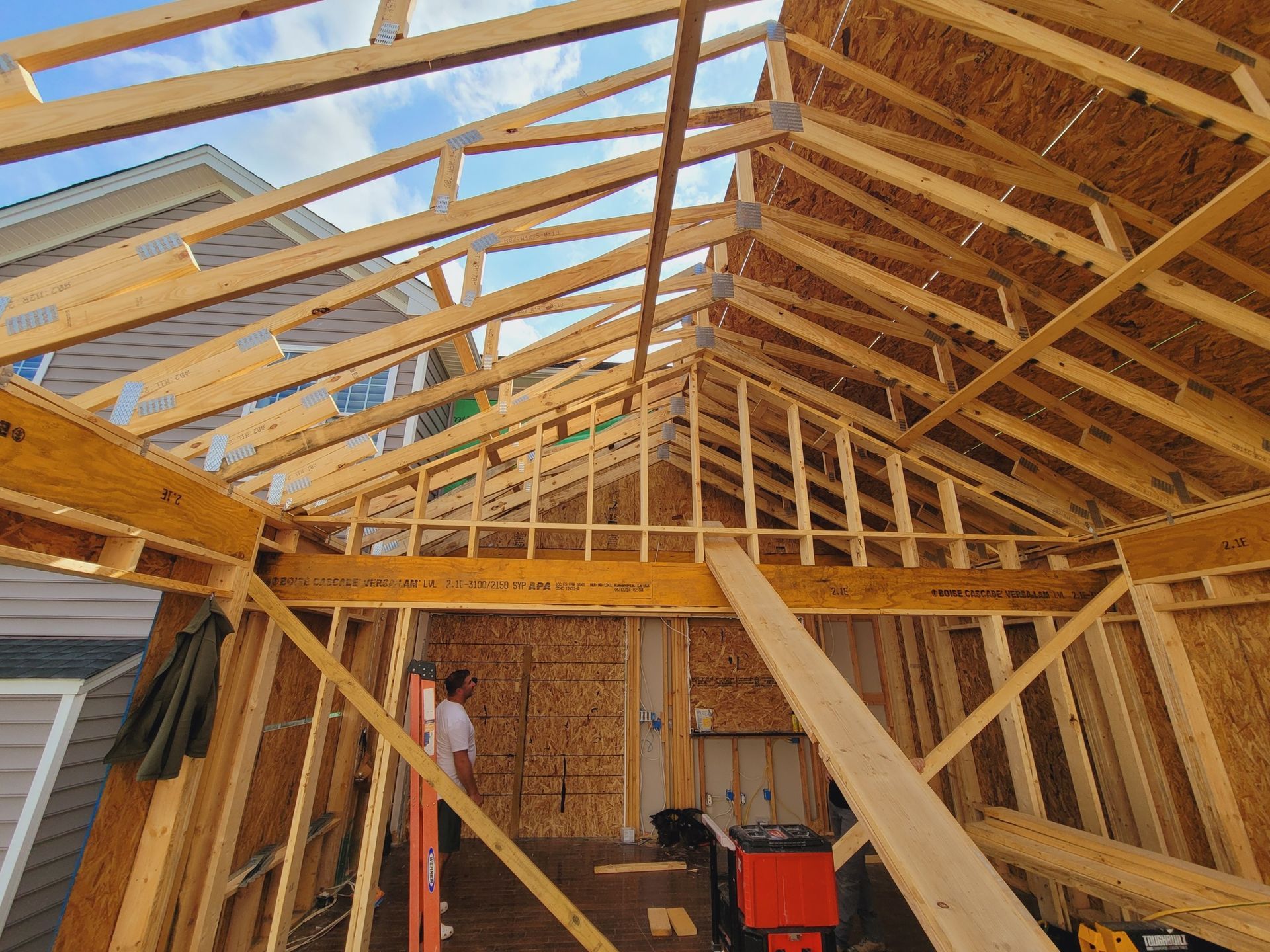 A man is standing in the middle of a wooden structure under construction.