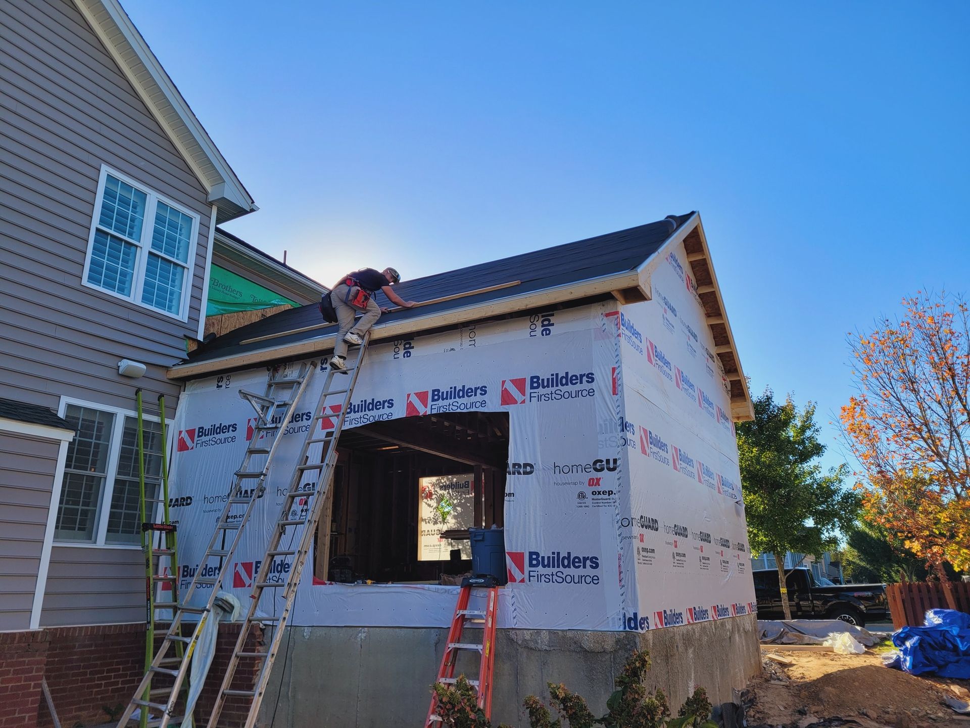 A man on a ladder is working on the roof of a house.