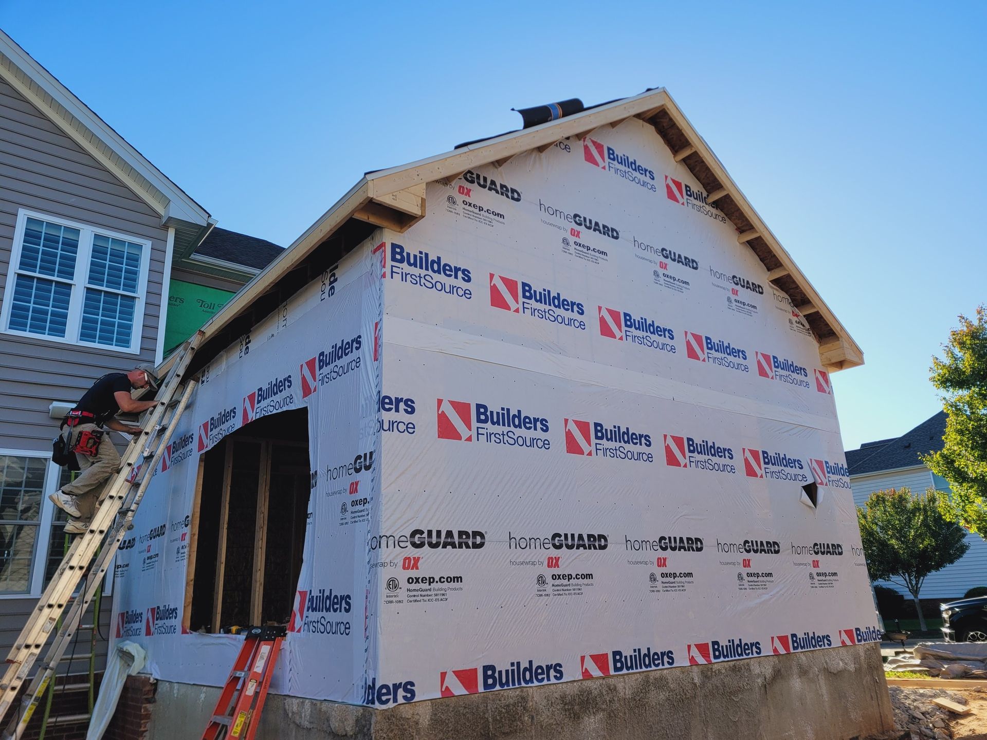 A man on a ladder is working on a house that is being built