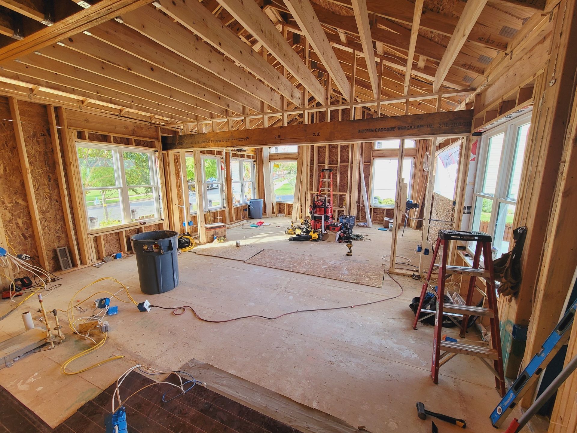 A room under construction with a ladder and a trash can.