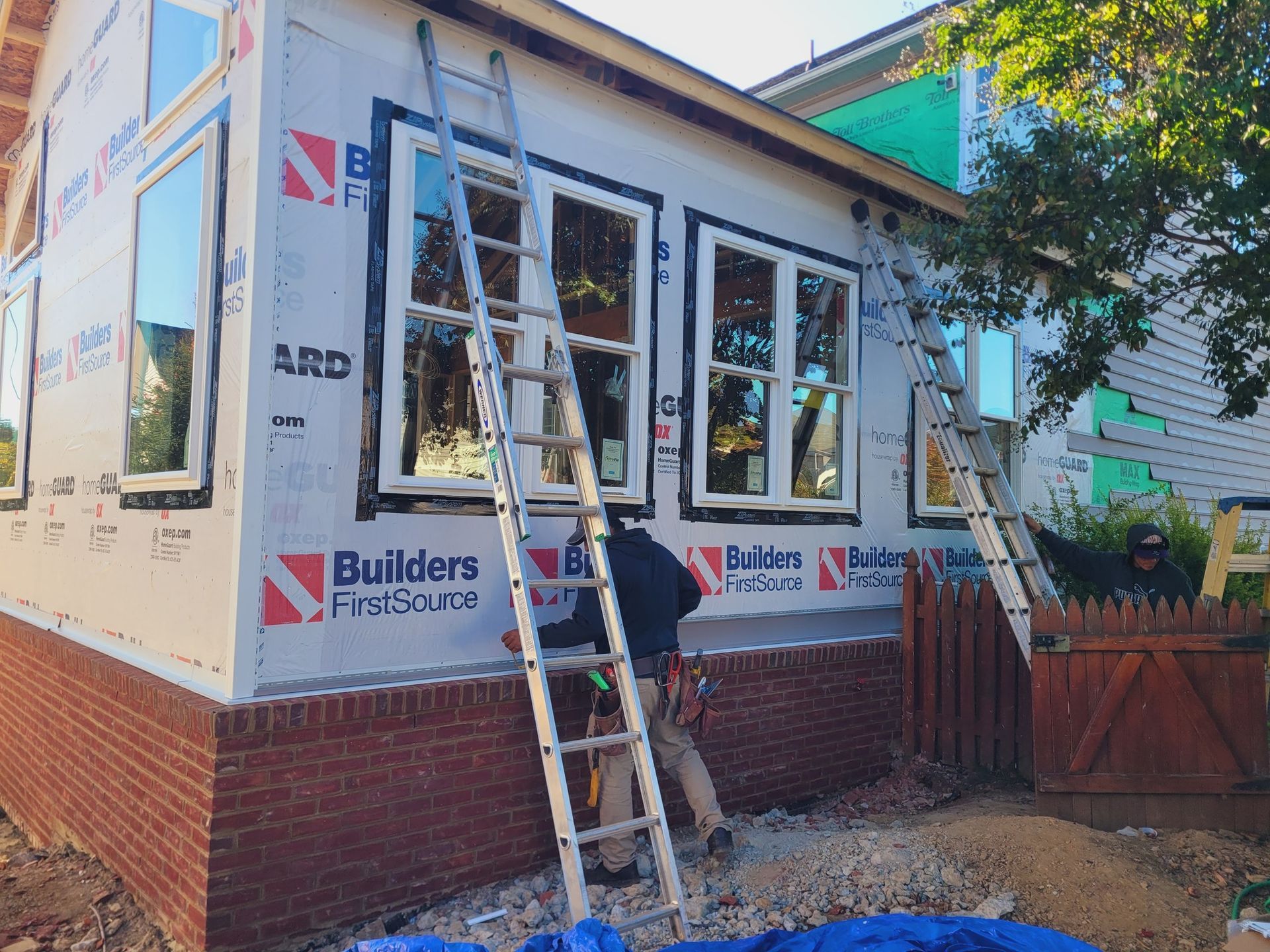 A man is standing on a ladder on the side of a house.