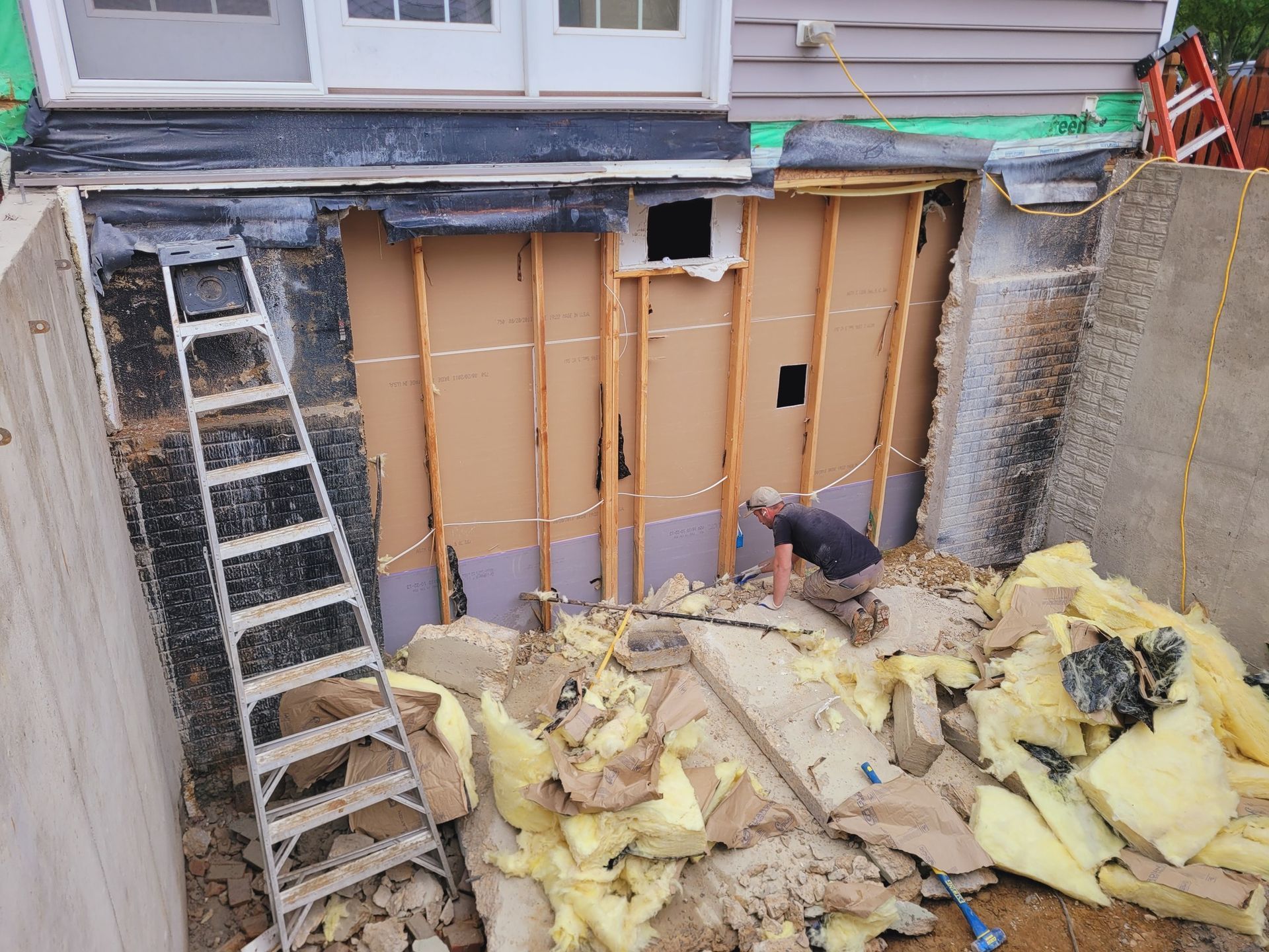 A man is working on a wall in a basement.