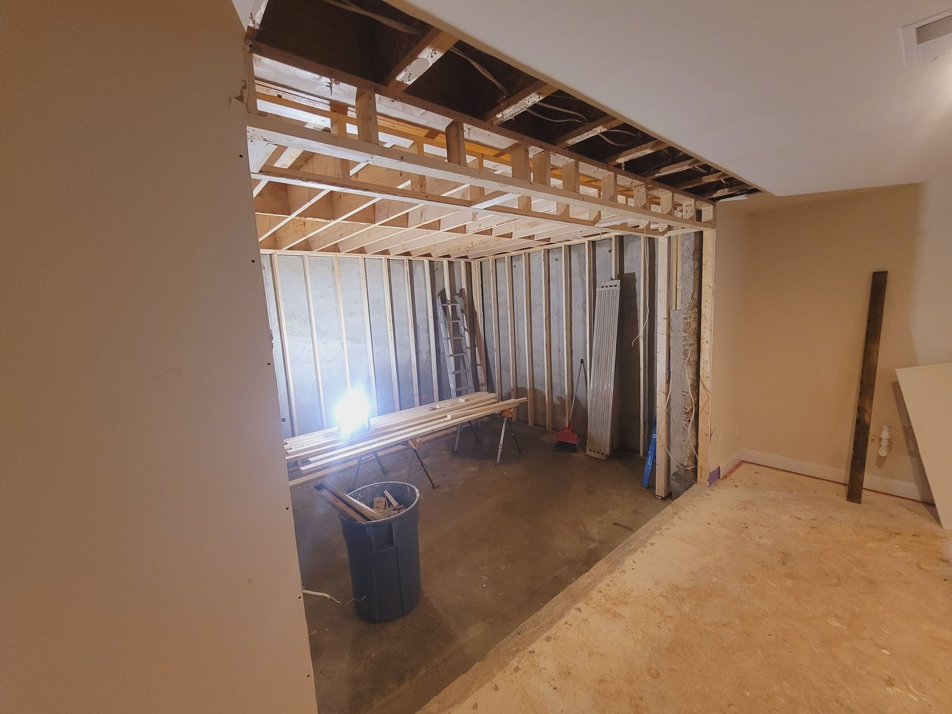 A room with a table and a trash can in it.