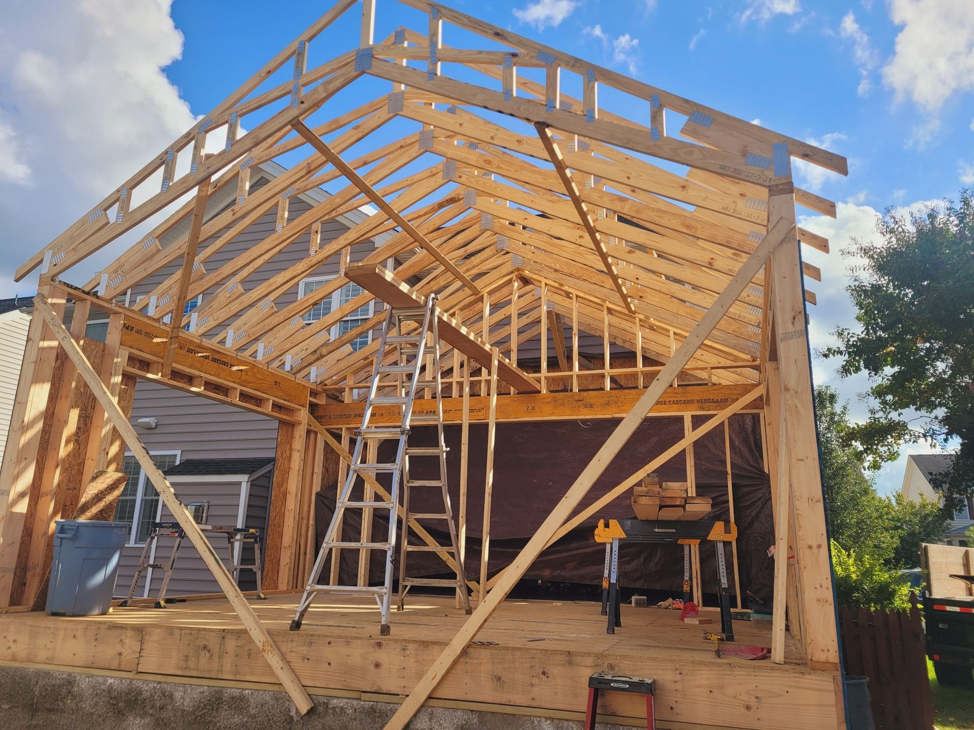 A house is being built with wooden beams and a ladder.