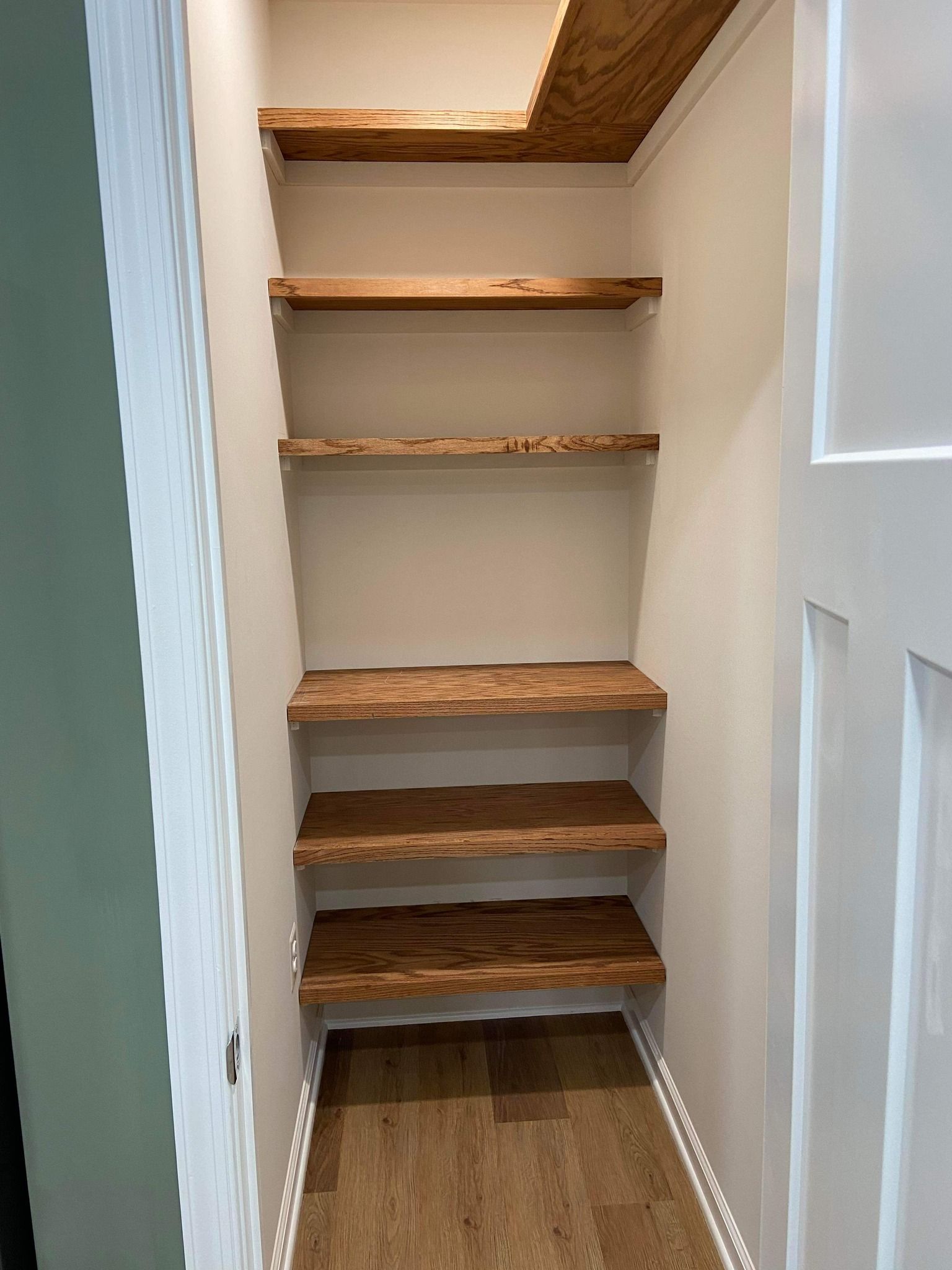 A small closet with wooden shelves and a wooden floor.