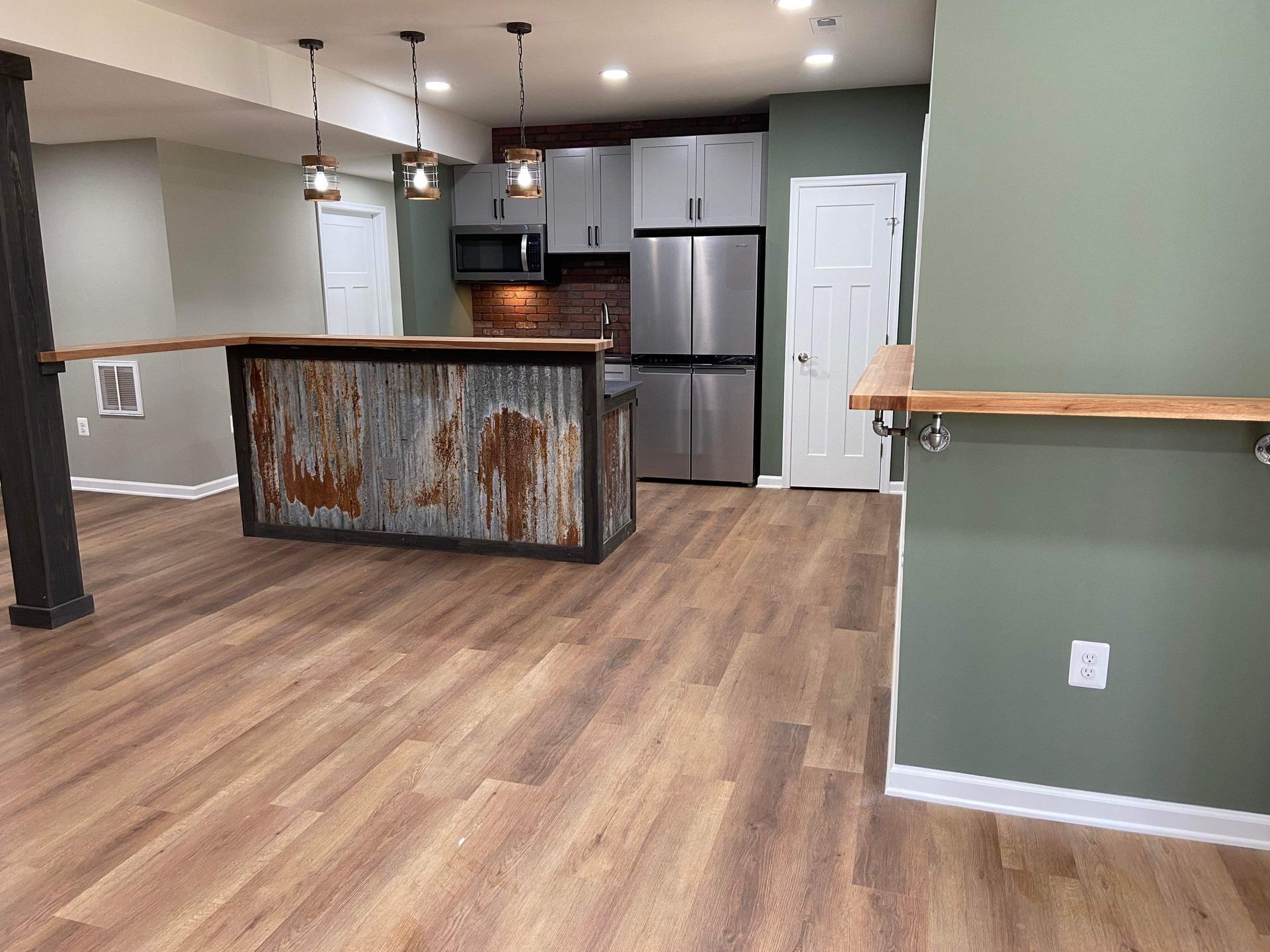 A kitchen in a basement with stainless steel appliances and wooden floors.