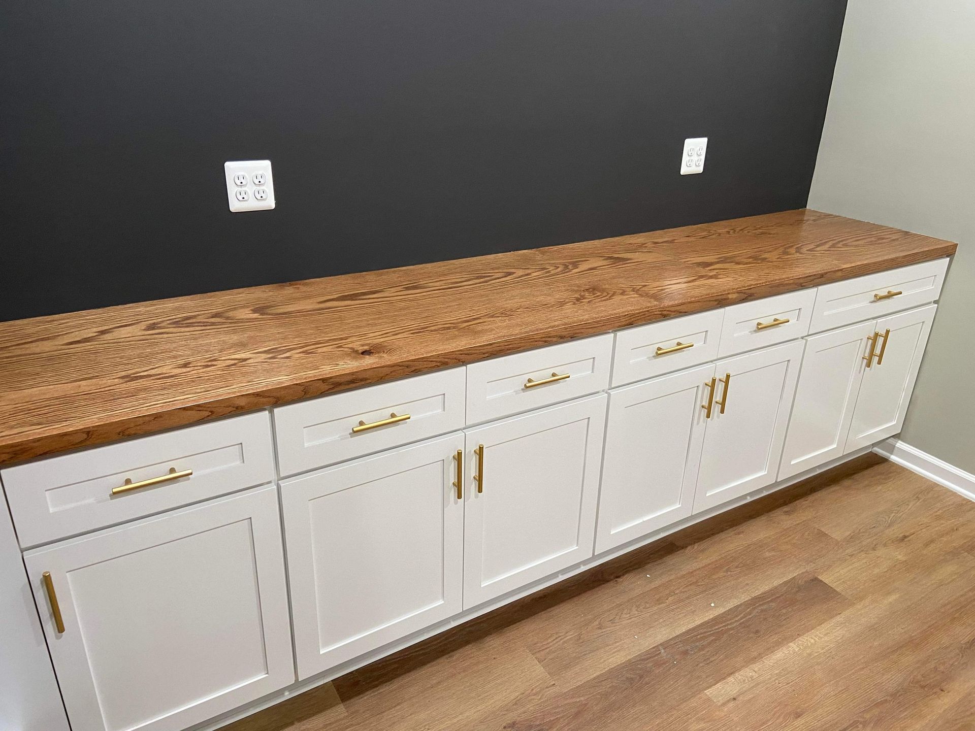 A kitchen with white cabinets and a wooden counter top.