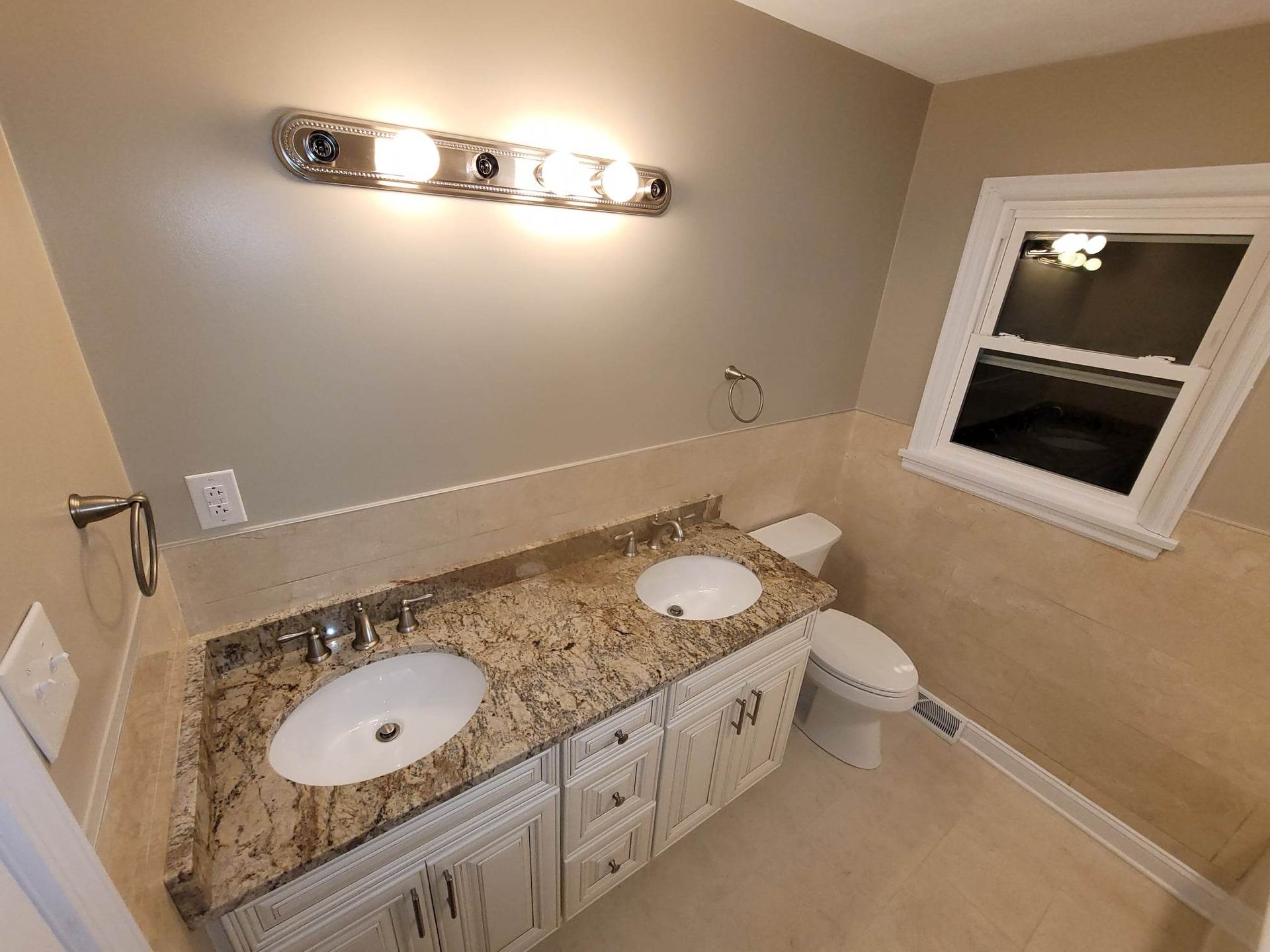 A bathroom with two sinks and a toilet