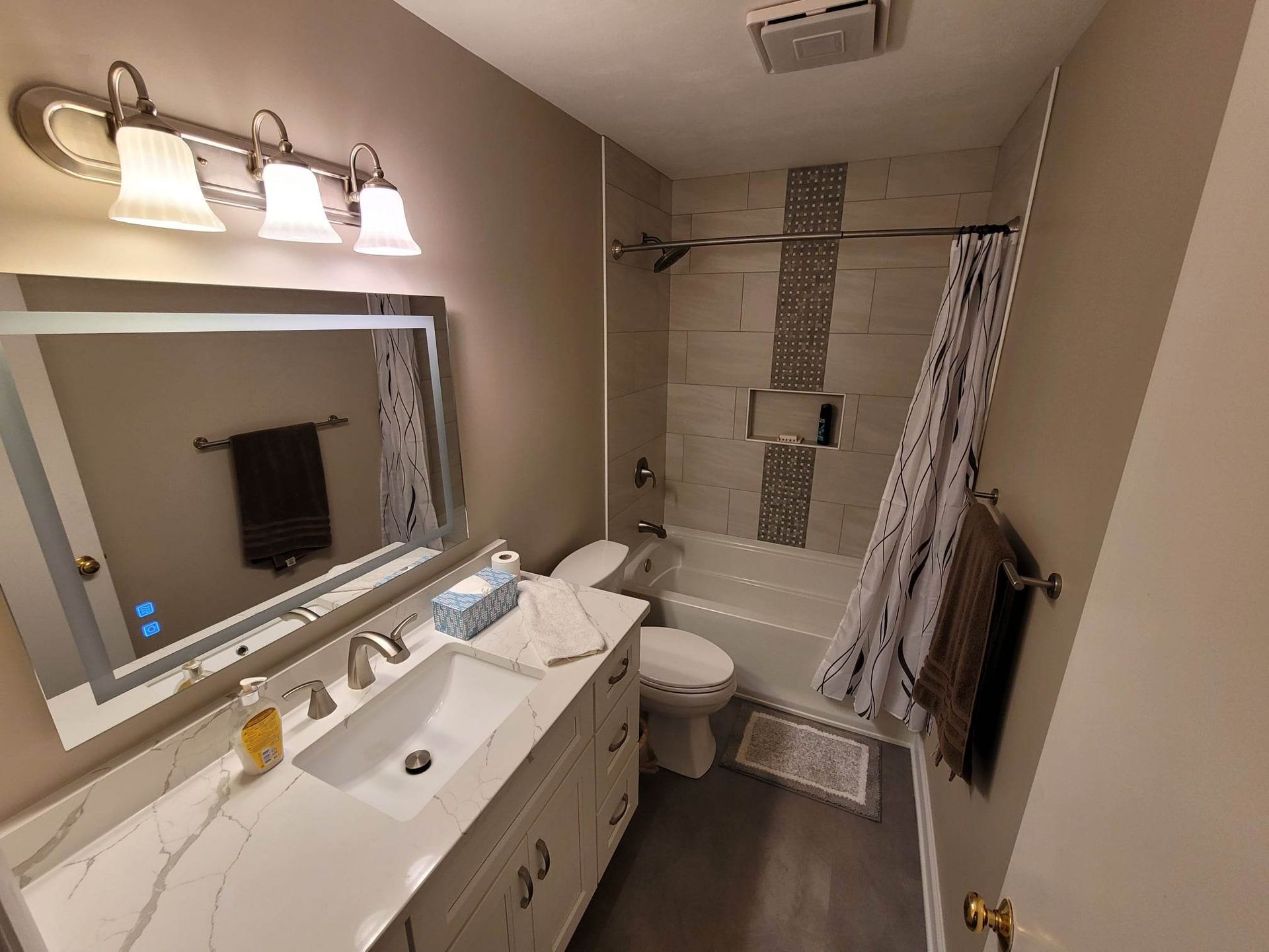 A bathroom with a sink , toilet , shower and mirror.