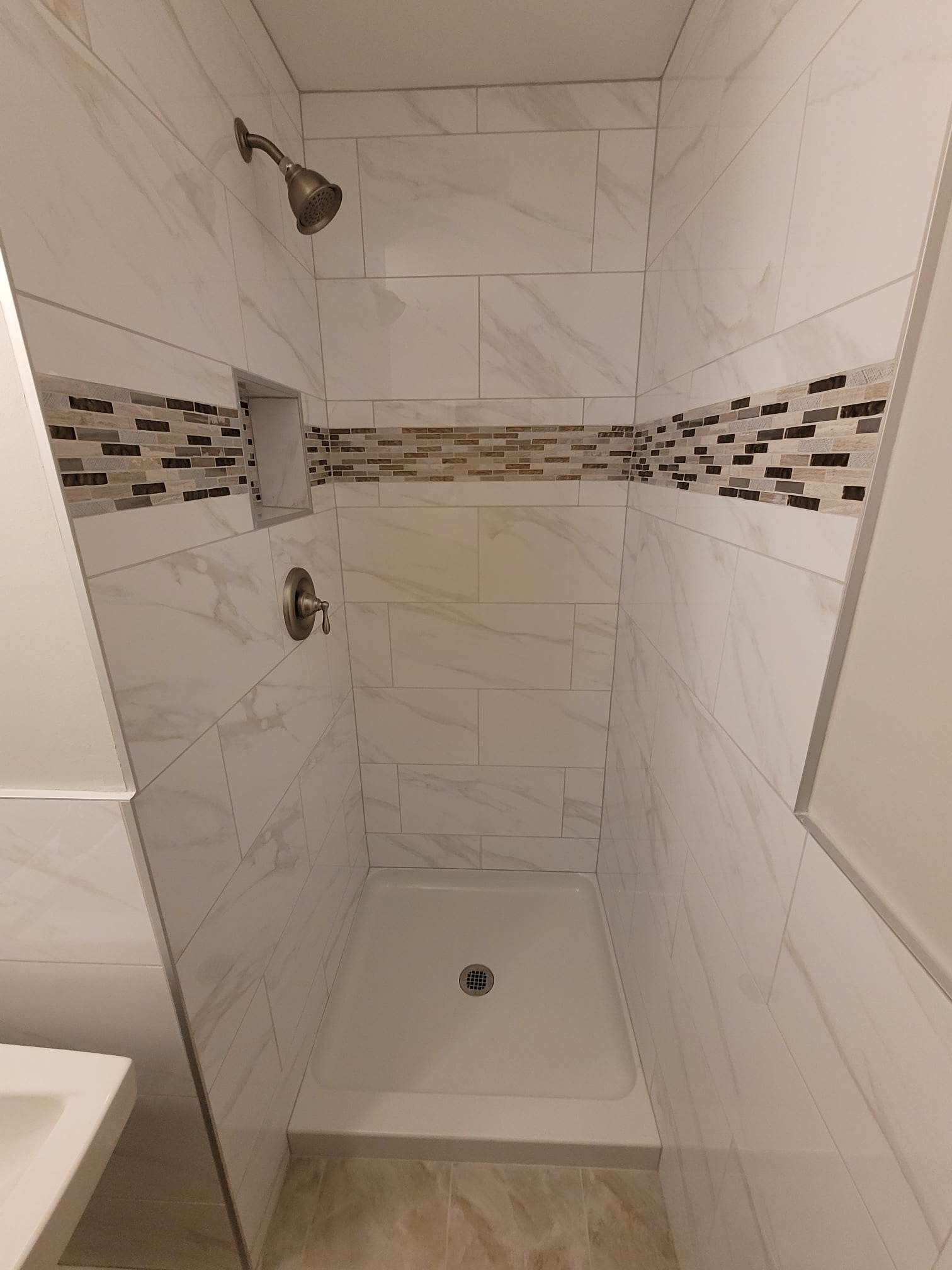 A bathroom with a walk in shower and a sink.