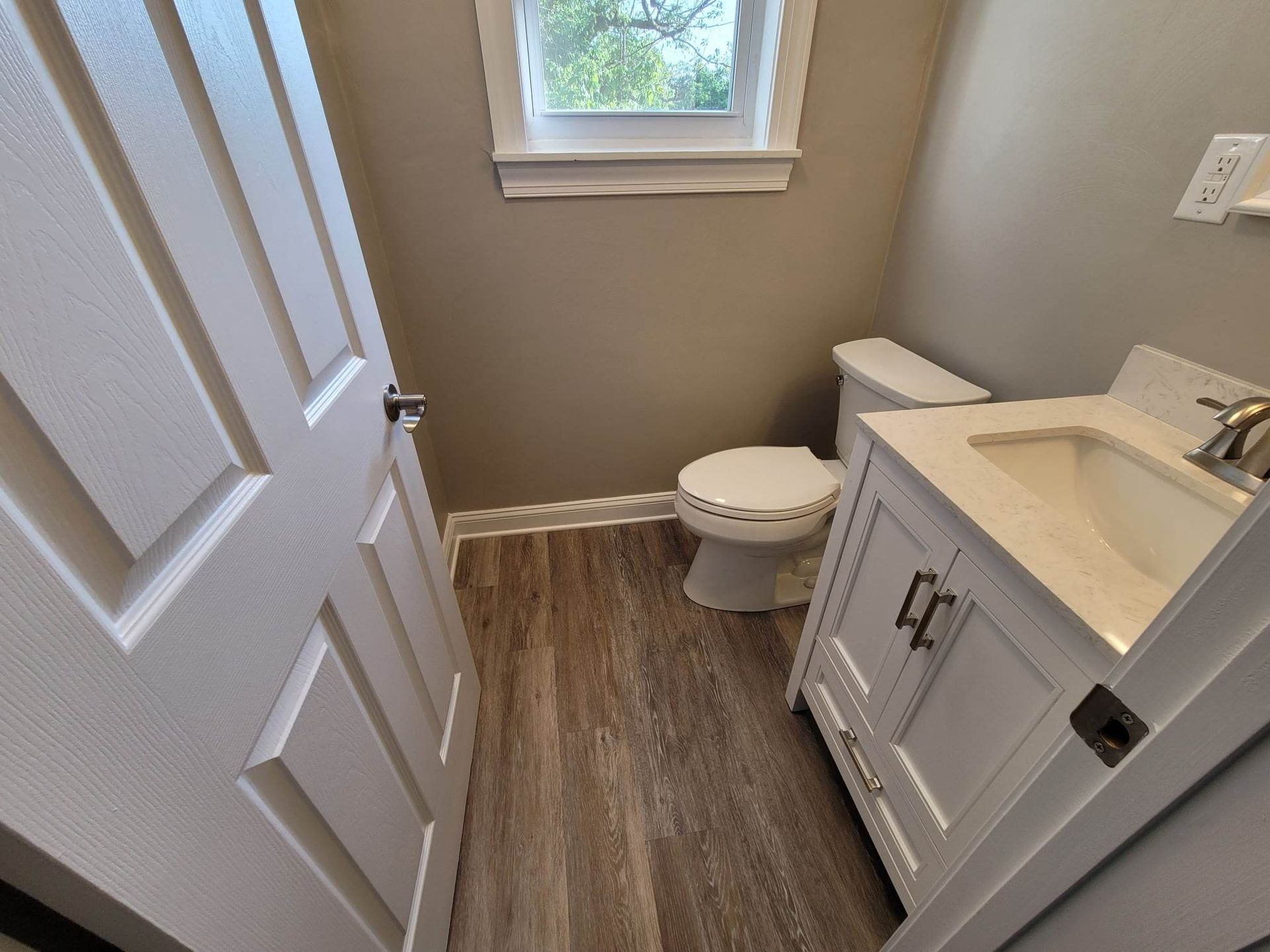 A bathroom with a toilet , sink and window.