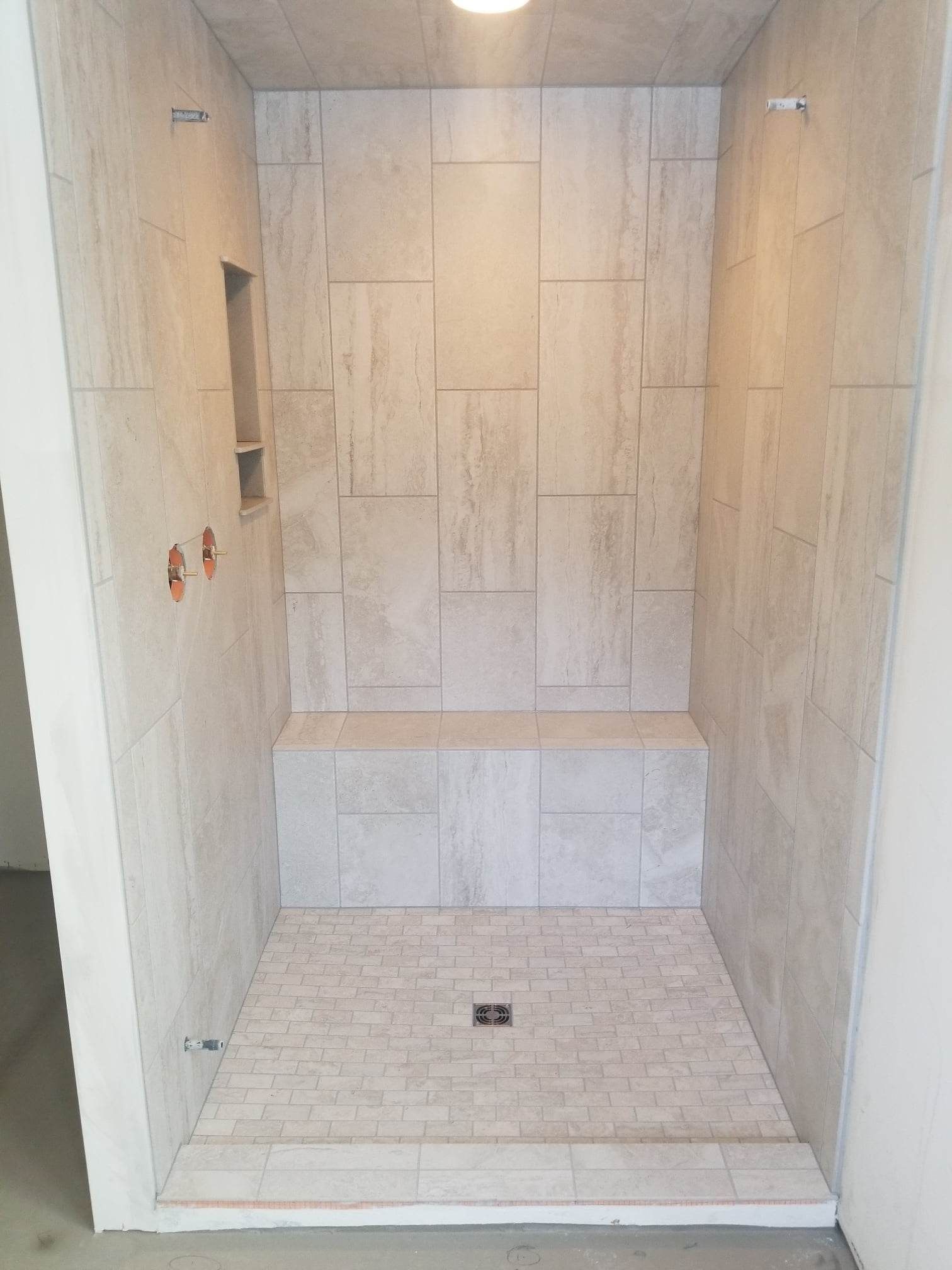 A shower stall with a bench in the middle of it.