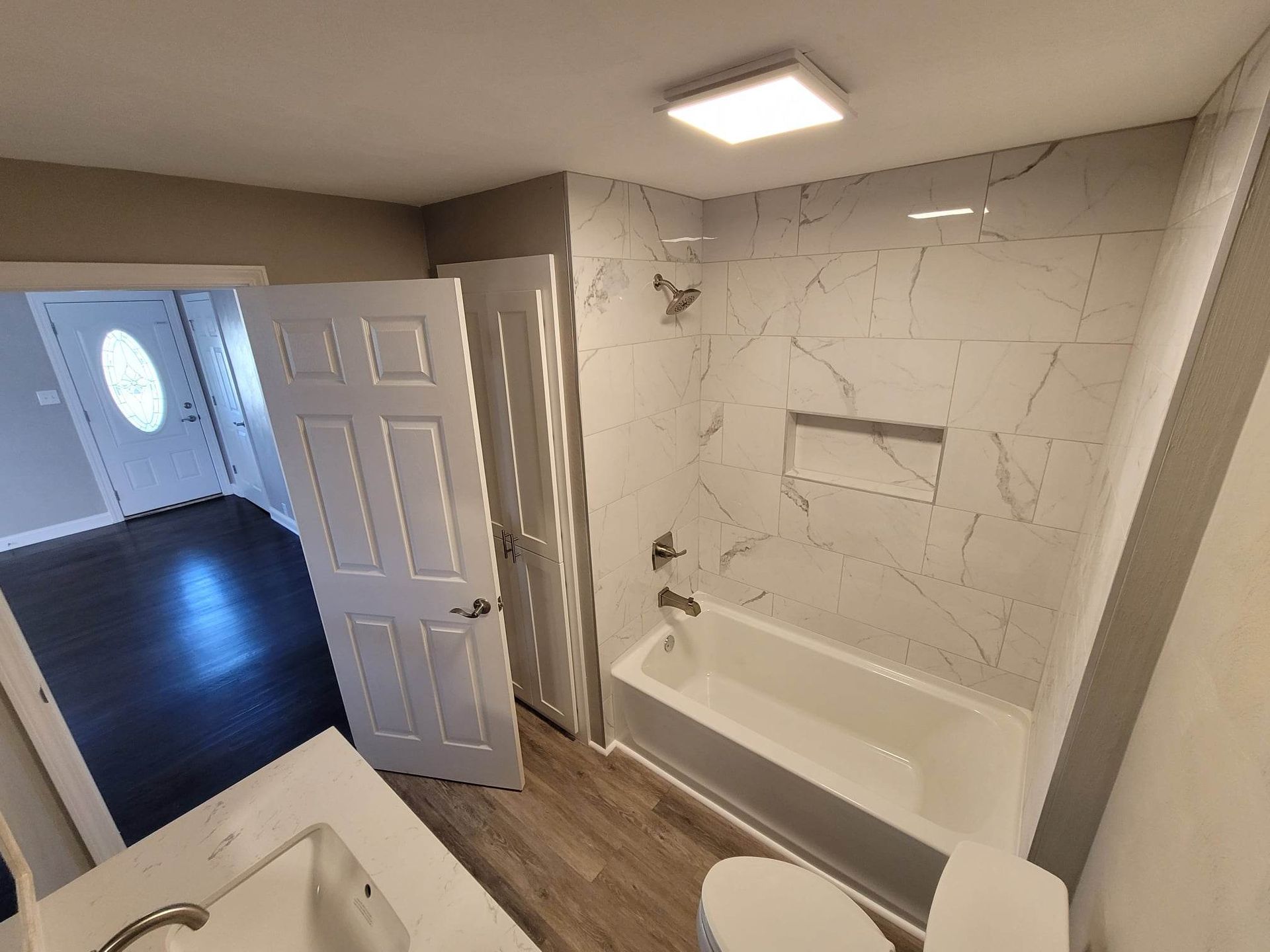 A bathroom with a tub , toilet , sink and mirror.