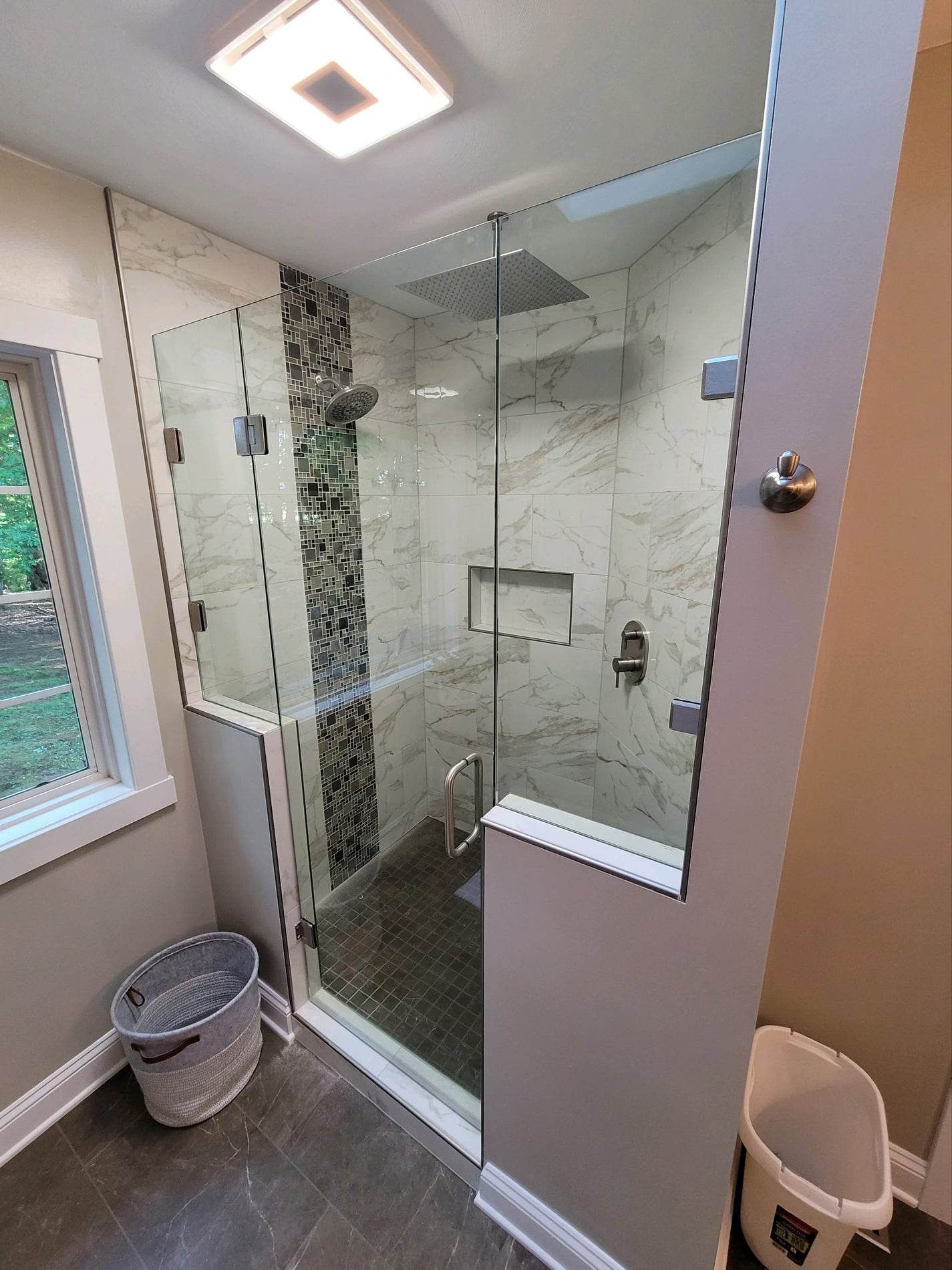 A bathroom with a walk in shower and a window.
