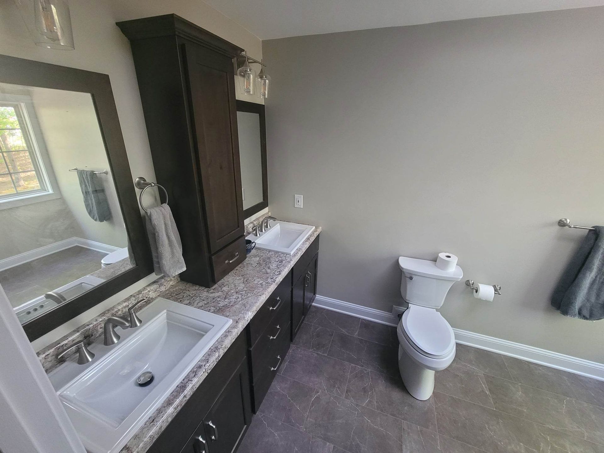 A bathroom with two sinks , a toilet and a mirror.