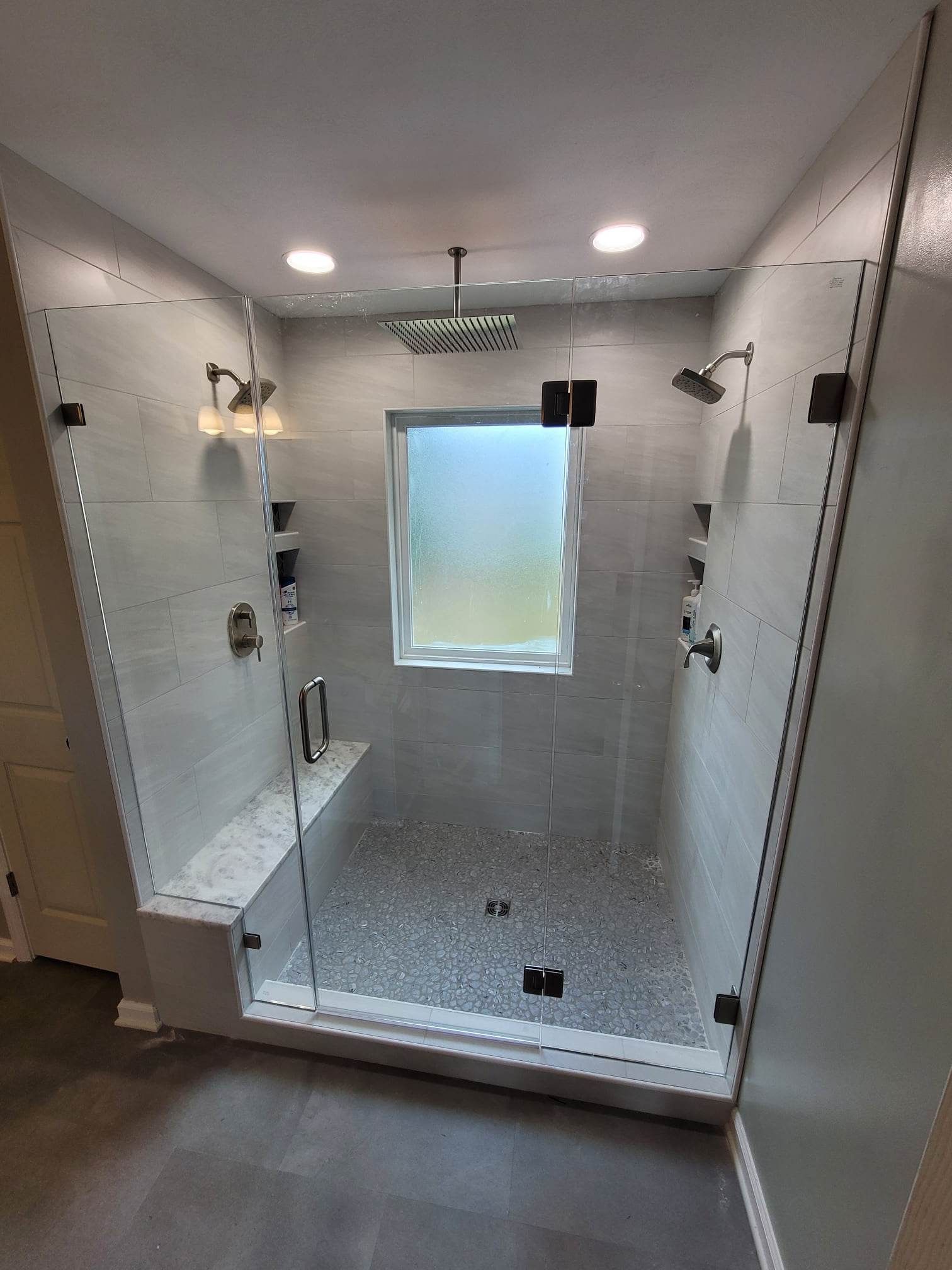 A bathroom with a walk in shower and a window.