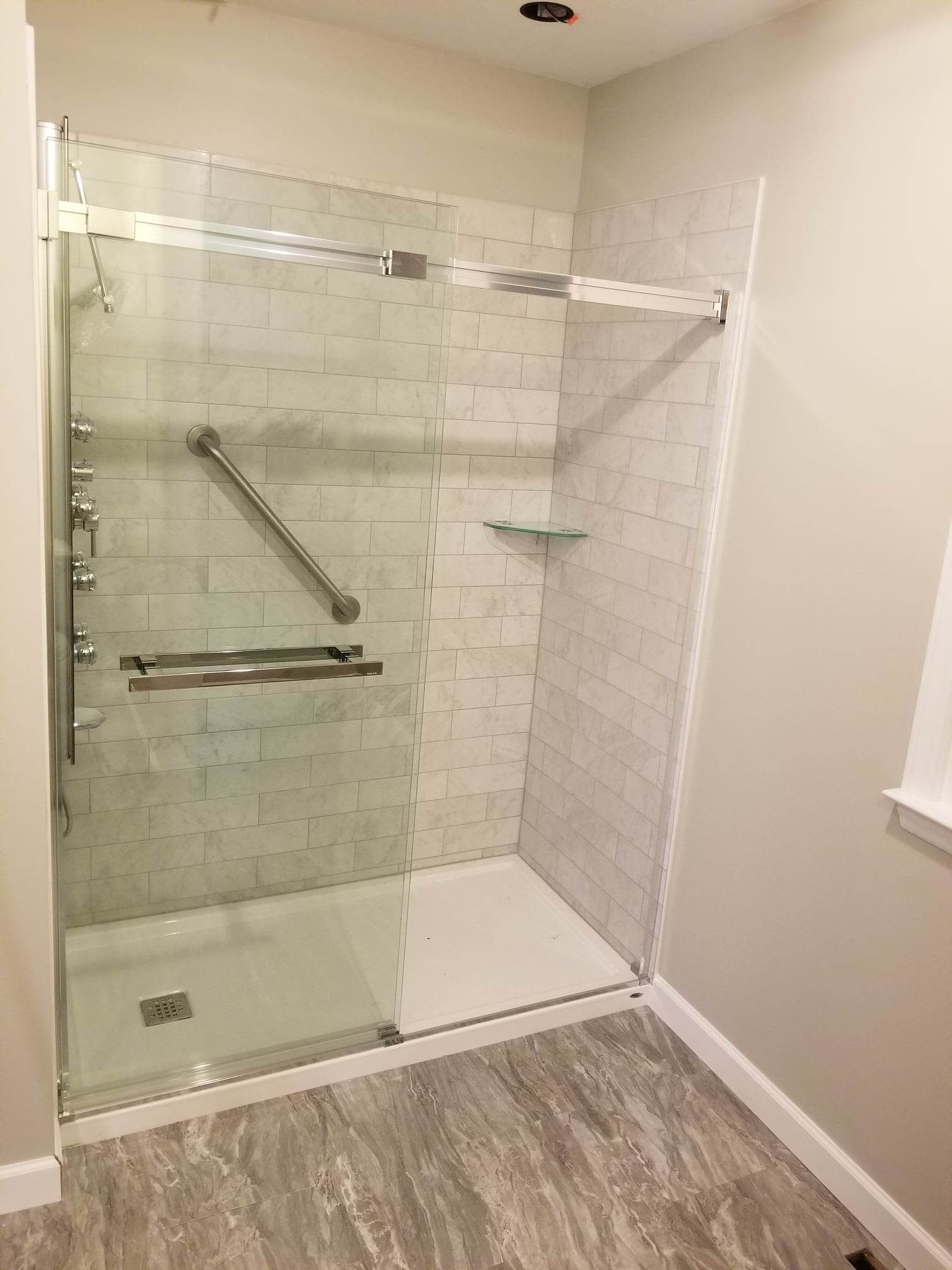 A bathroom with a walk in shower and a window.