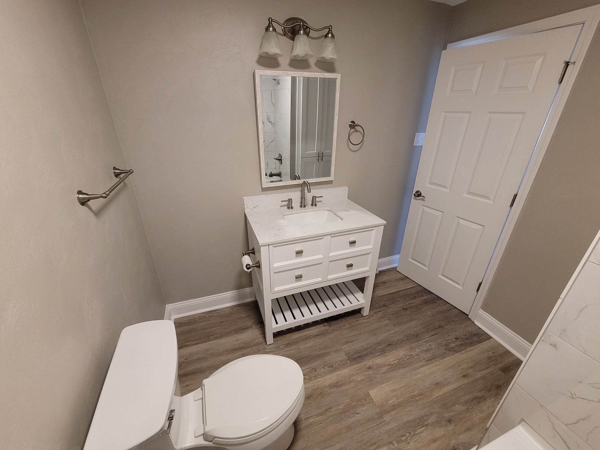 A bathroom with a toilet , sink and mirror.