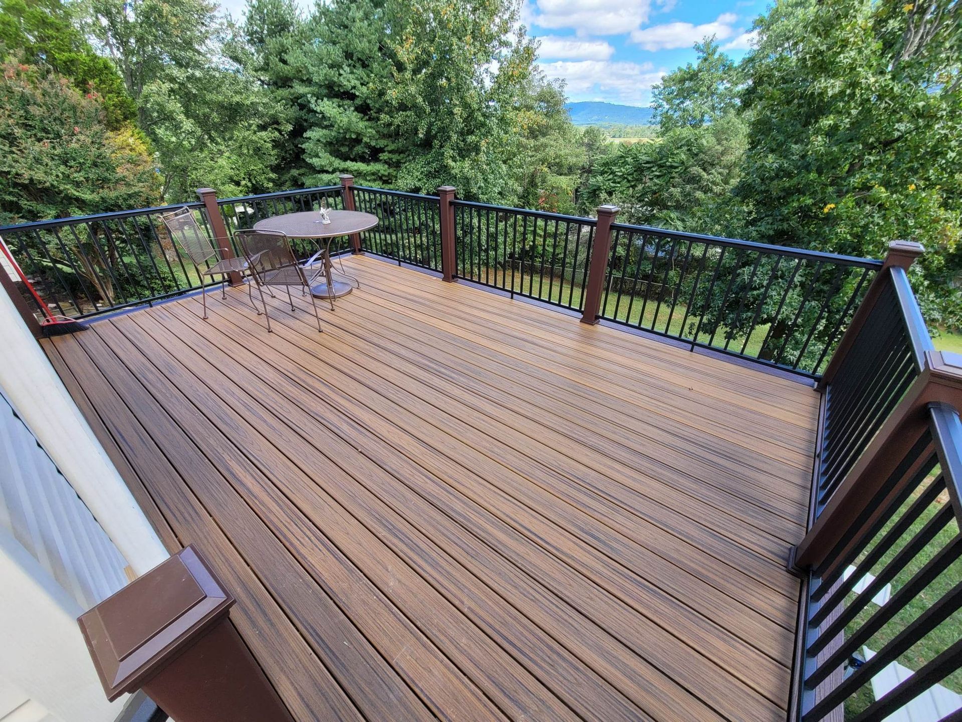 A large wooden deck with a table and chairs on it.