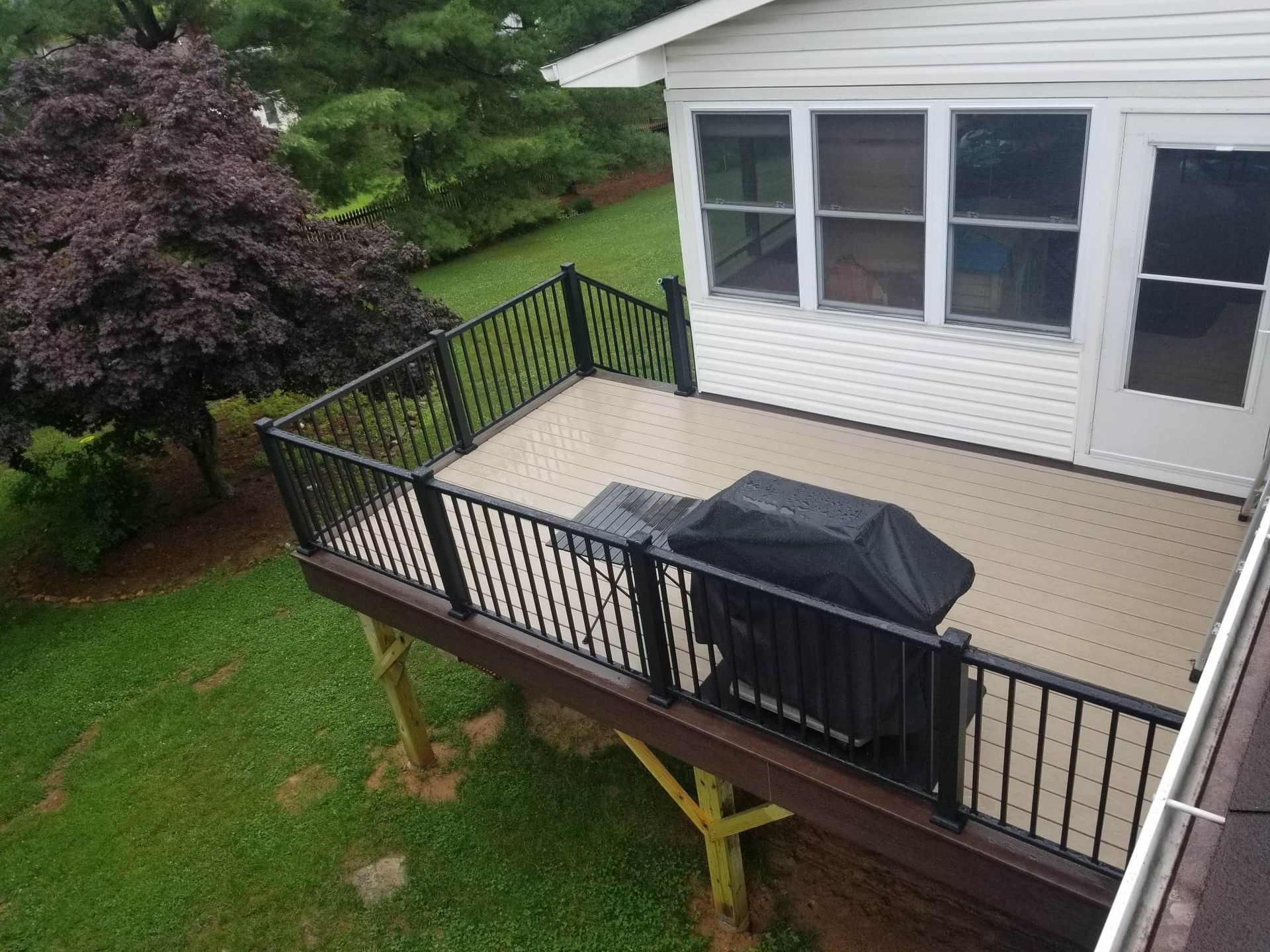An aerial view of a deck with a grill on it next to a house.