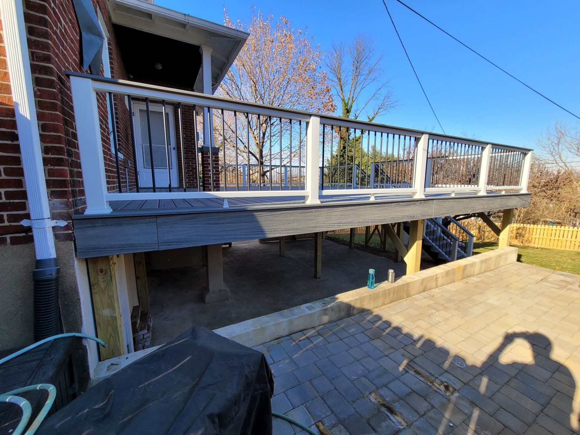 A large deck is sitting underneath a brick house.