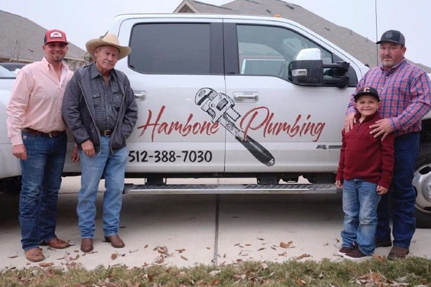 A group of men are standing in front of a plumbing truck.