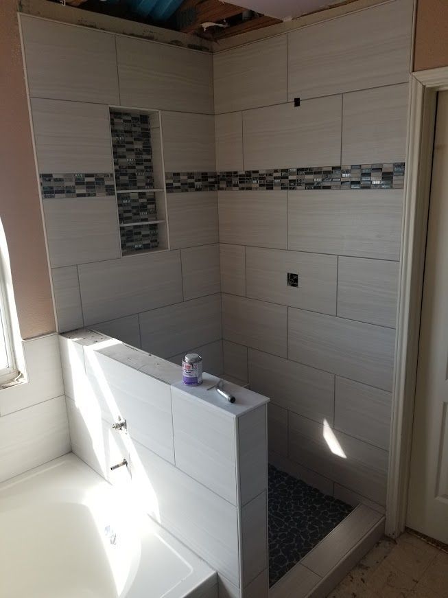 A bathroom with white tiles and a walk in shower.