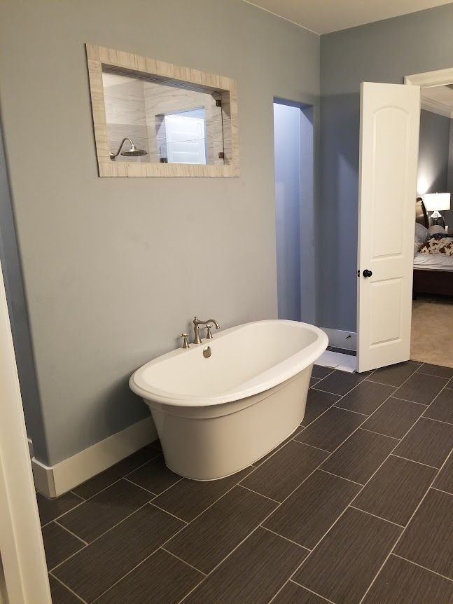 A bathroom with a bathtub and a mirror on the wall.