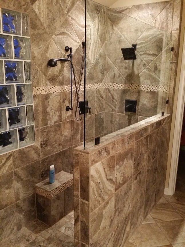 A bathroom with a walk in shower with a glass door.