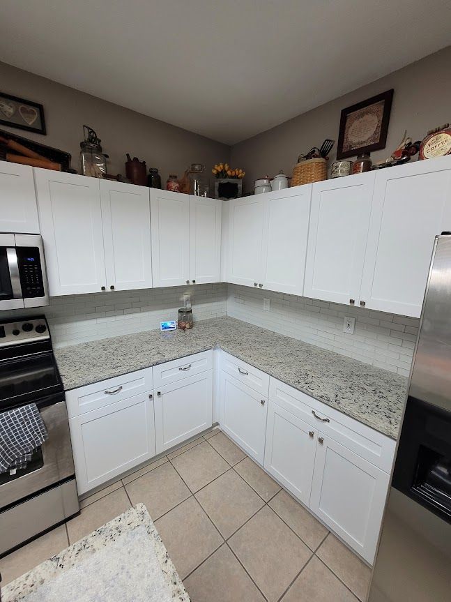 A kitchen with white cabinets, granite counter tops, and stainless steel appliances.