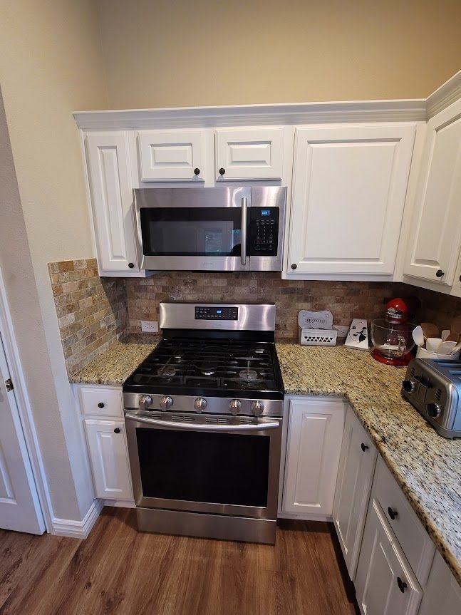 A kitchen with stainless steel appliances and white cabinets.