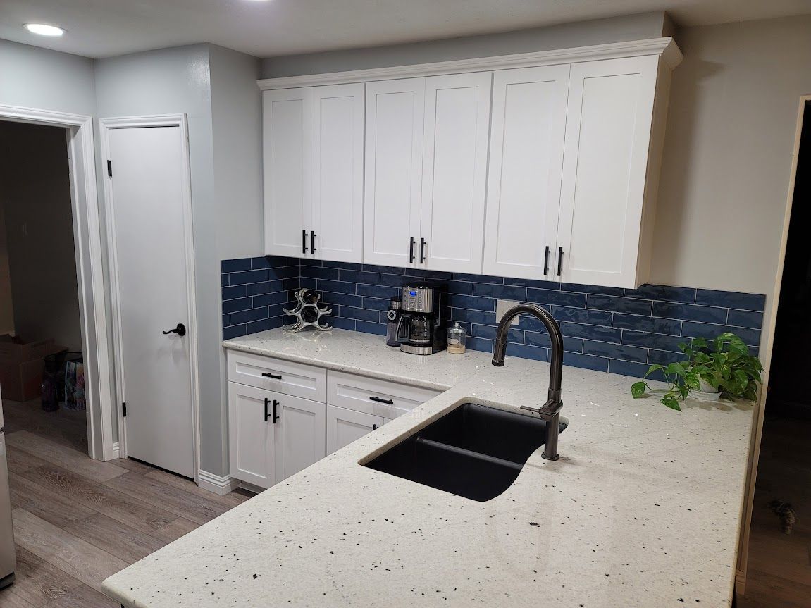 A kitchen with white cabinets and a black sink.