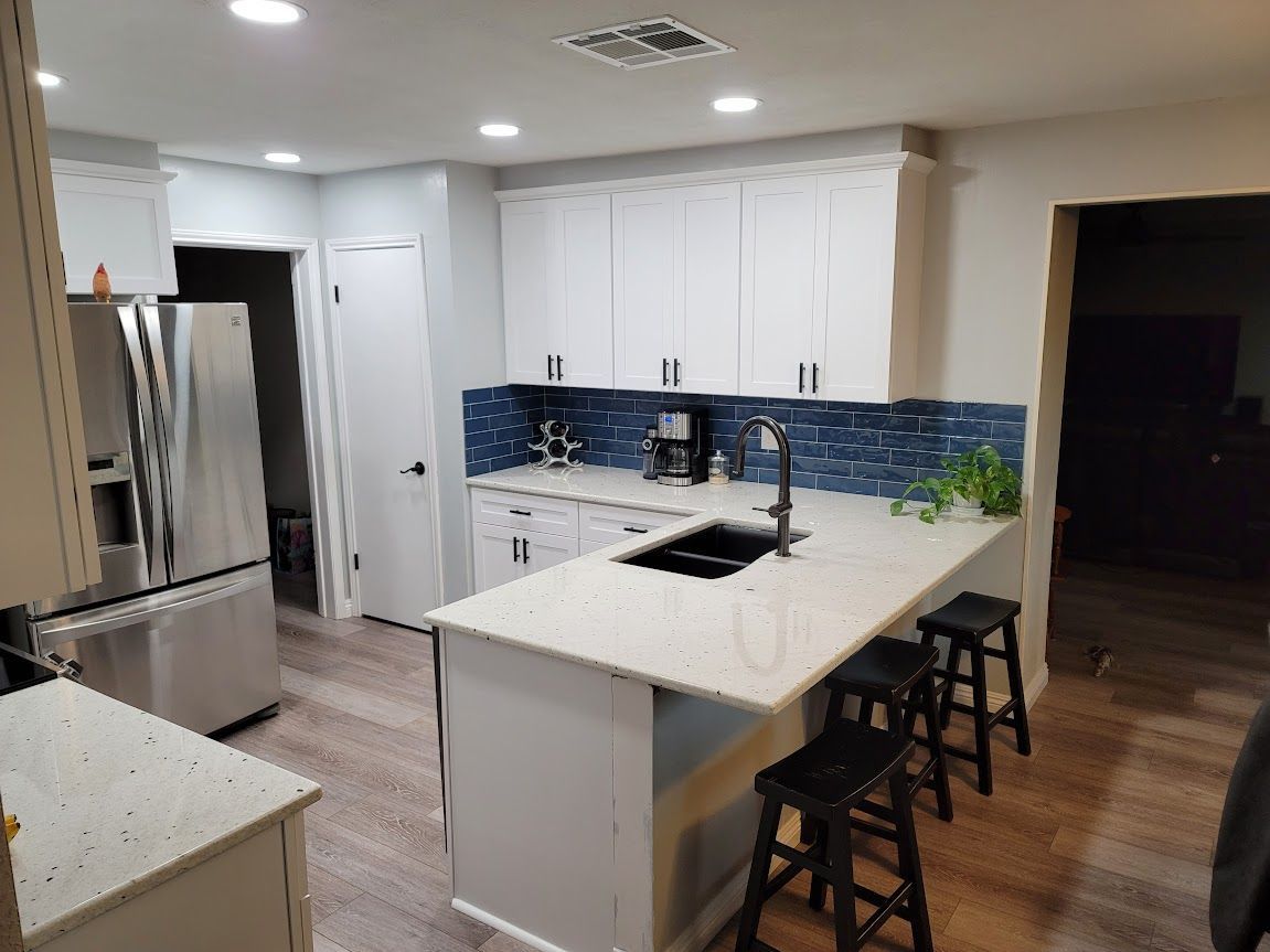 A kitchen with white cabinets, stainless steel appliances, and a large island.