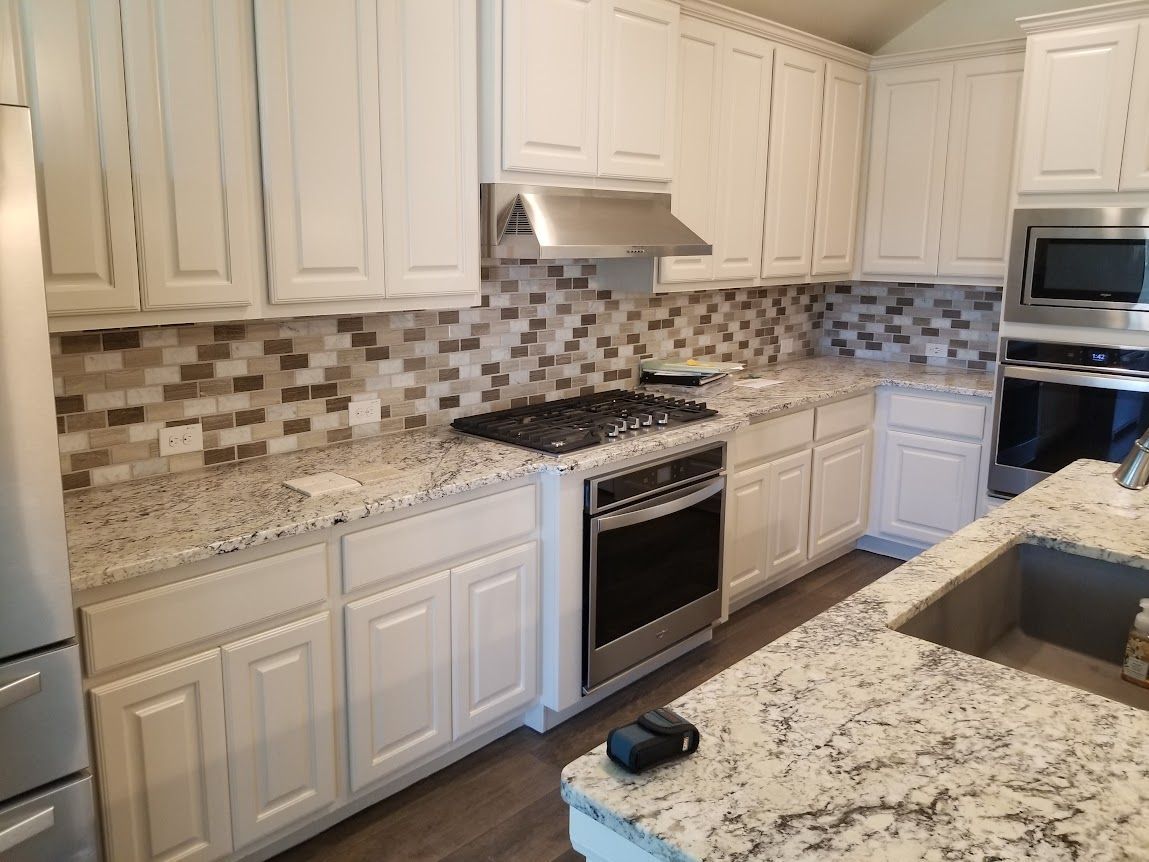 A kitchen with white cabinets, granite counter tops, stainless steel appliances, and a sink.