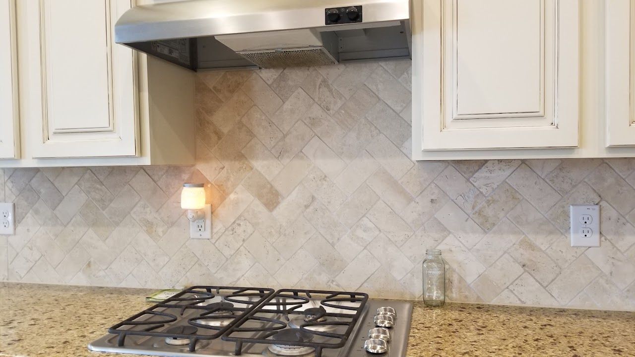 A kitchen with a stove top oven and a hood above it.