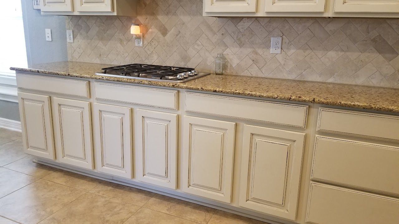 A kitchen with white cabinets and granite counter tops.