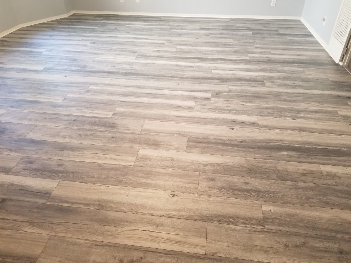A room with a wooden laminate floor and white walls