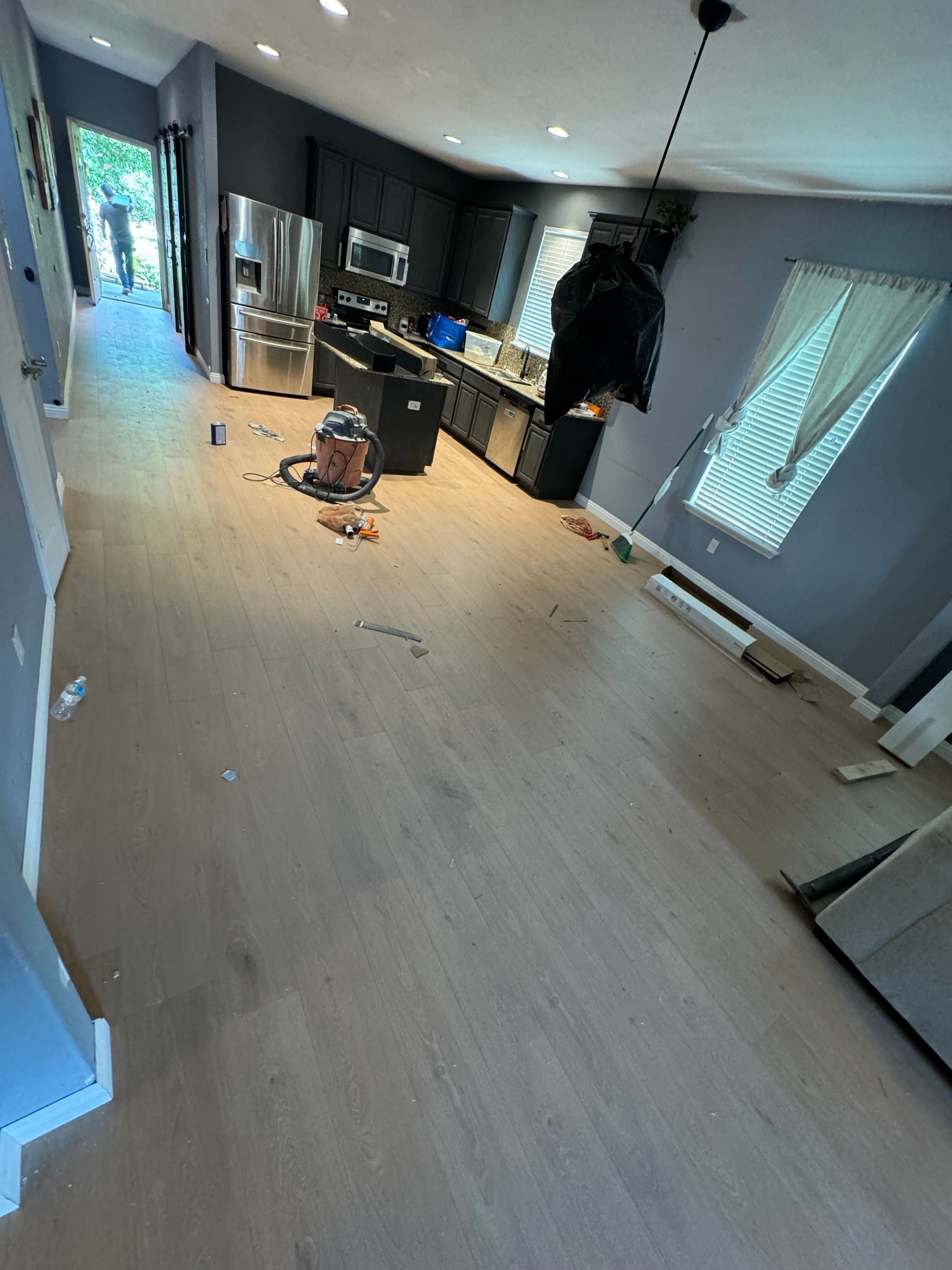 A kitchen with hardwood floors and a vacuum cleaner on the floor.