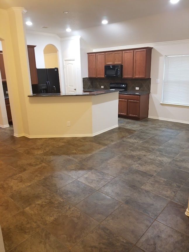 A kitchen with wooden cabinets and a tile floor