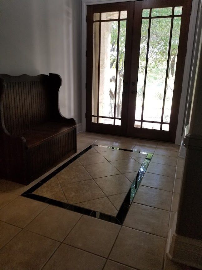 A hallway with a bench and a tiled floor in front of a door