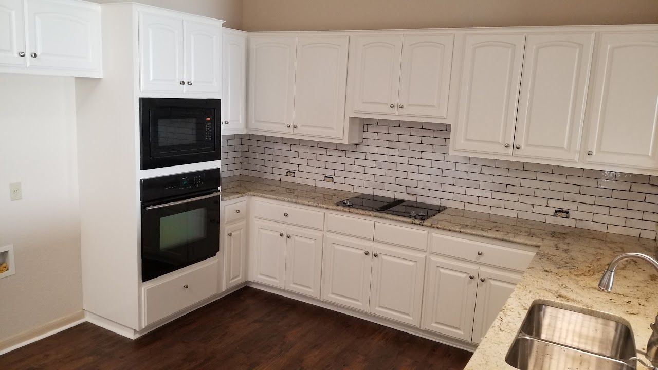 A kitchen with white cabinets, granite countertops, stainless steel appliances, and a sink