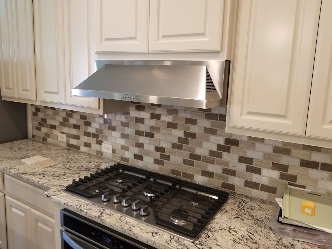 A kitchen with a stove top oven and a hood above it