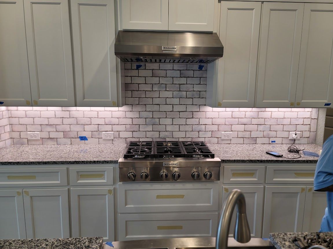 A kitchen with white cabinets and a stove-top oven