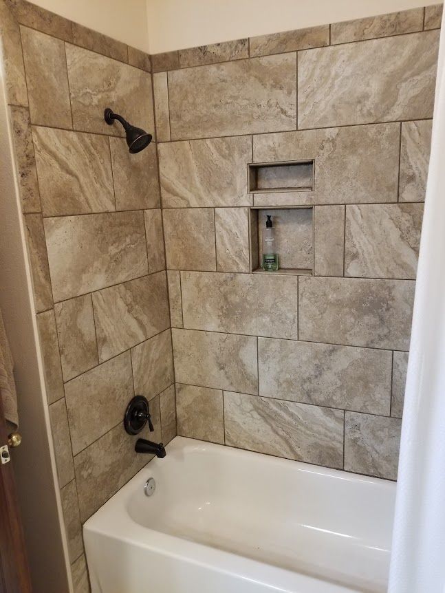Bathtub with a shower and tiled walls