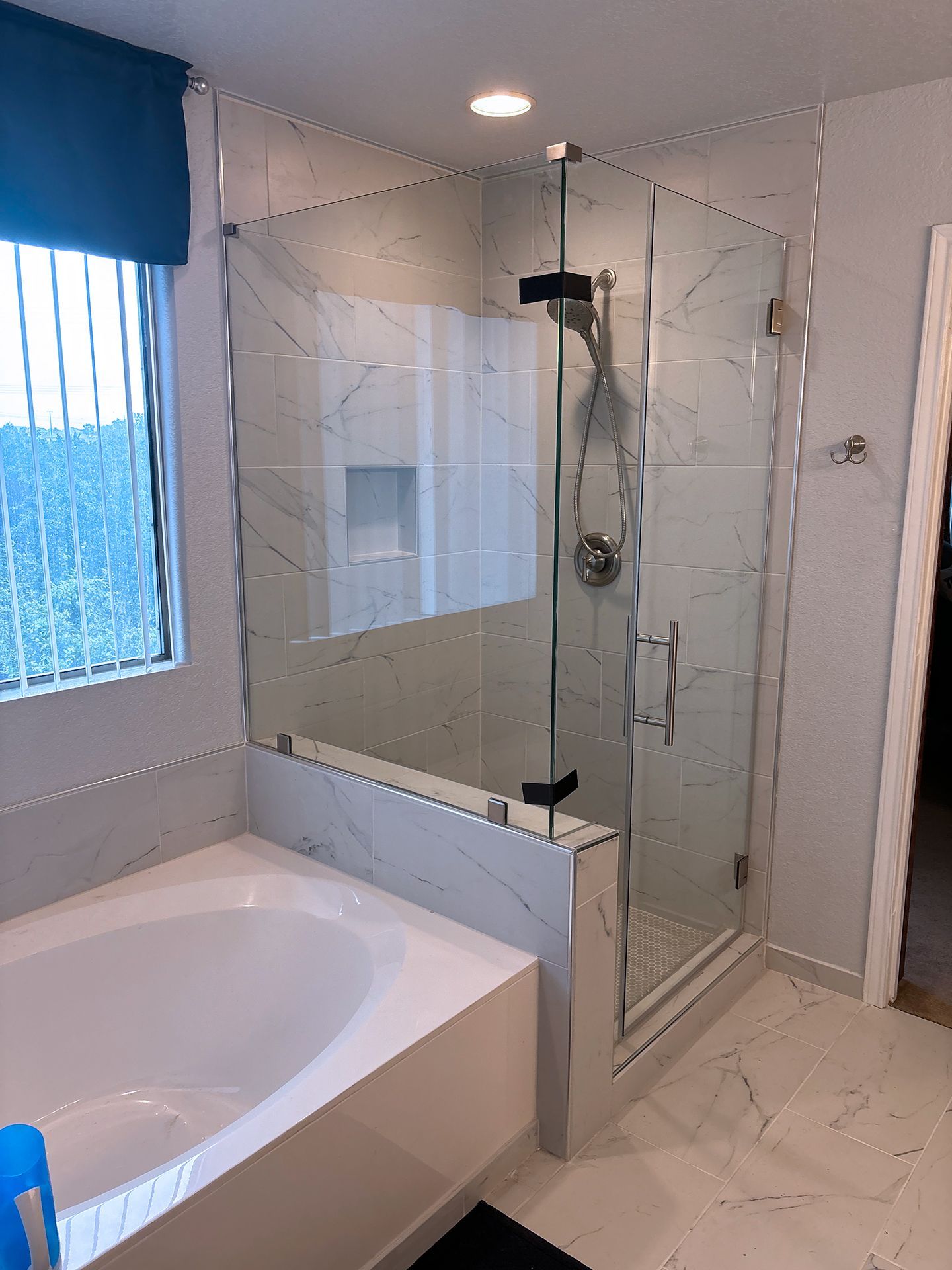 Walk-in shower with glass door beside a bathtub