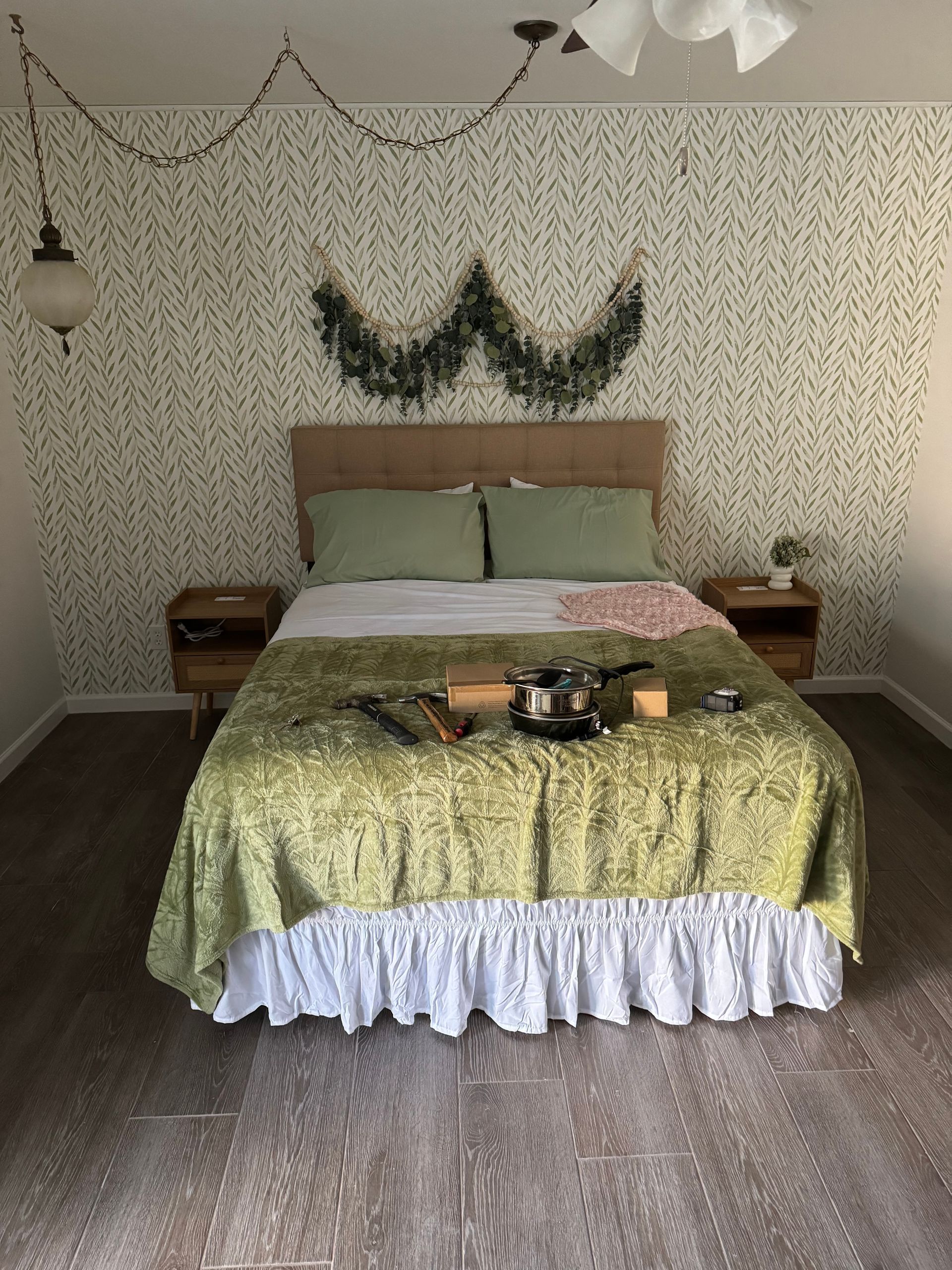 A bed with a green comforter and white ruffled skirt is in a bedroom.